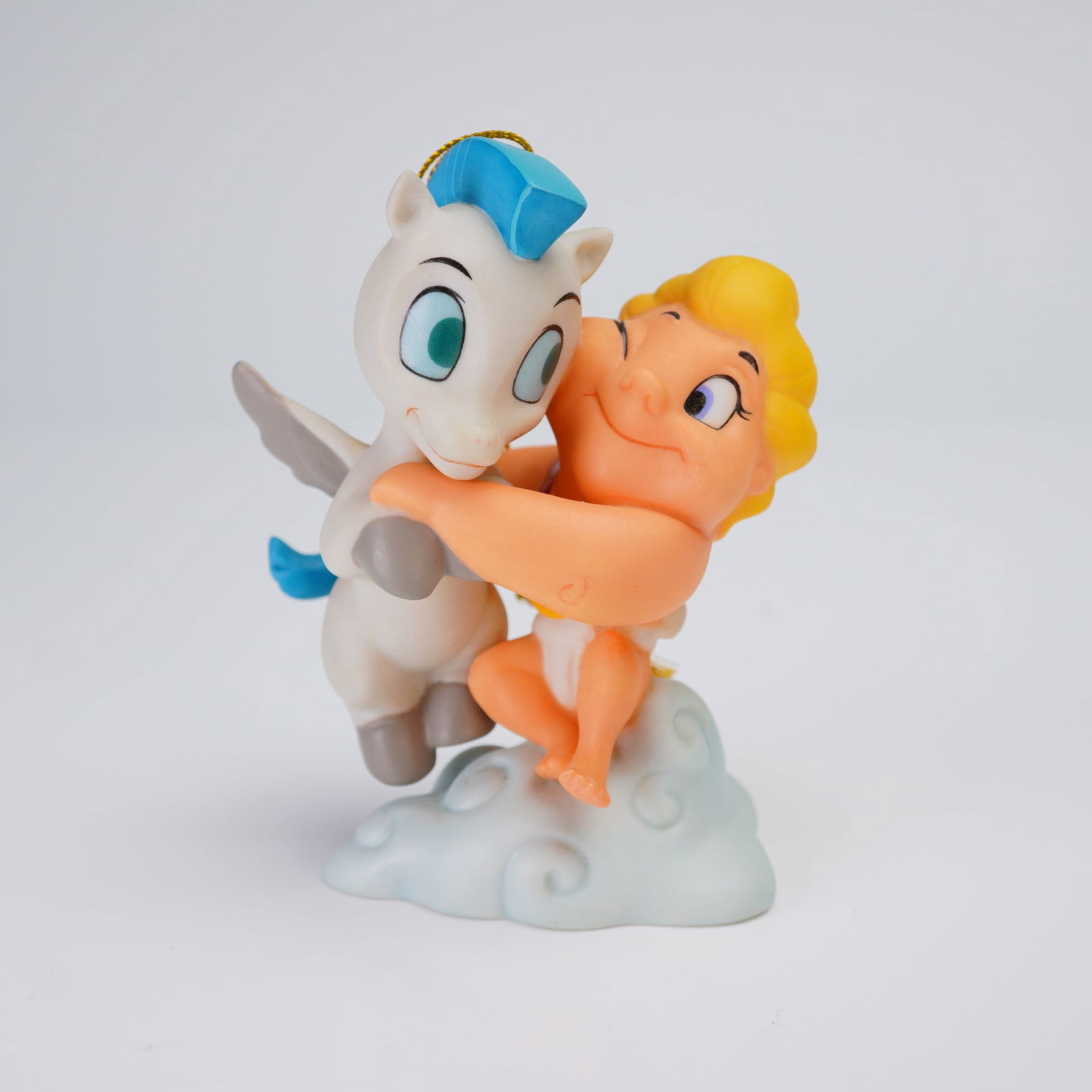 Walt Disney Classics Collection Ornament, Hercules A Gift From The Gods: The painted porcelain or ceramic piece shows the two characters embracing while standing on a pale blue cloud formation. The ornament features a gold cord loop attached for hanging. The piece is accom