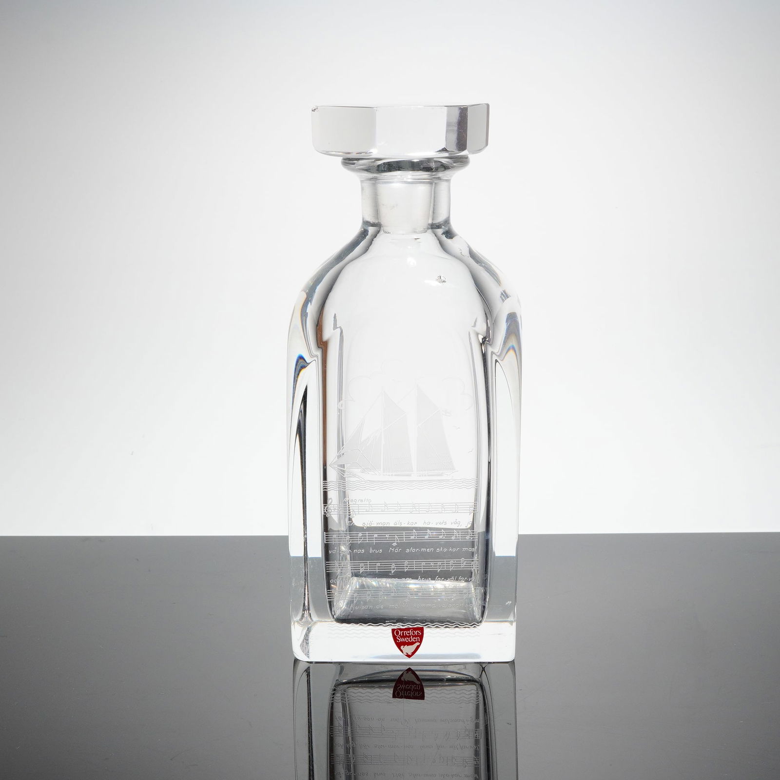 Orrefors Crystal Decanter Etched Sailing Ship & Music w/ Stopper: A heavy, clear lead crystal decanter with matching faceted stopper, attributed to Orrefors, Sweden. The decanter is crafted in a modern block-form design with rounded shoulders and a thick base. The f