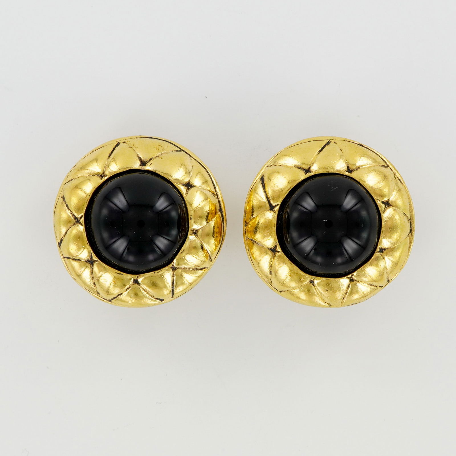 Chanel Black Cabochon Gold Tone Clip Earrings: Formed in a circular profile, these vintage Chanel earrings are produced in gold tone metal and set with black cabochon centers. Each earring includes clip backs, and the reverse shows the oval cartou
