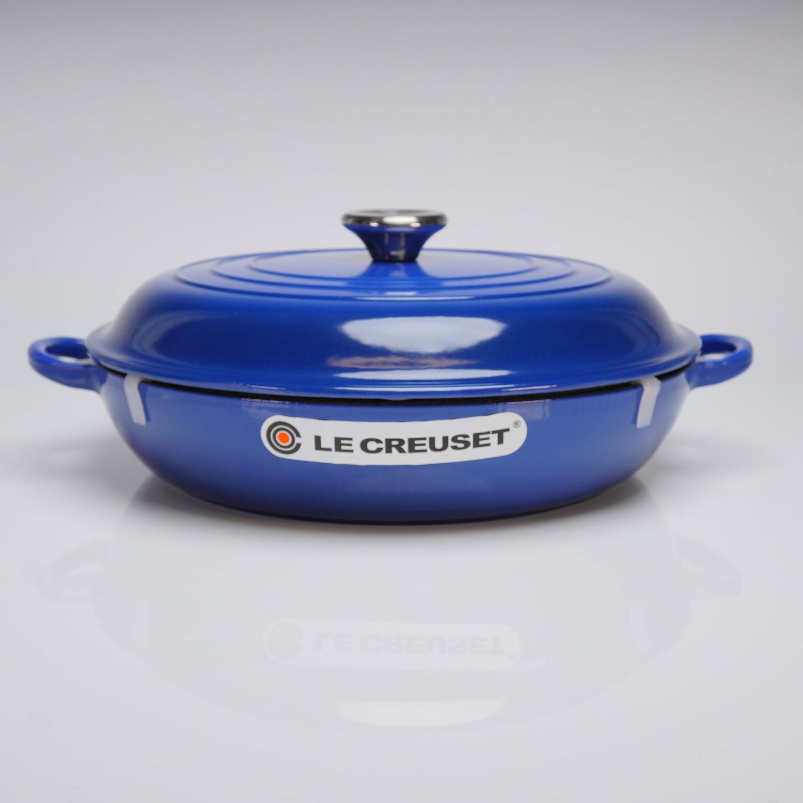 Le Creuset Cast Iron Shallow 3.5Qt. Casserole Braiser with Lid, Cobalt Blue: Le Creuset Signature Cast Iron Shallow Casserole-Braiser with Lid. The piece is constructed of enameled cast iron, featuring a glossy Cobalt Blue exterior finish and a contrasting light sand interior