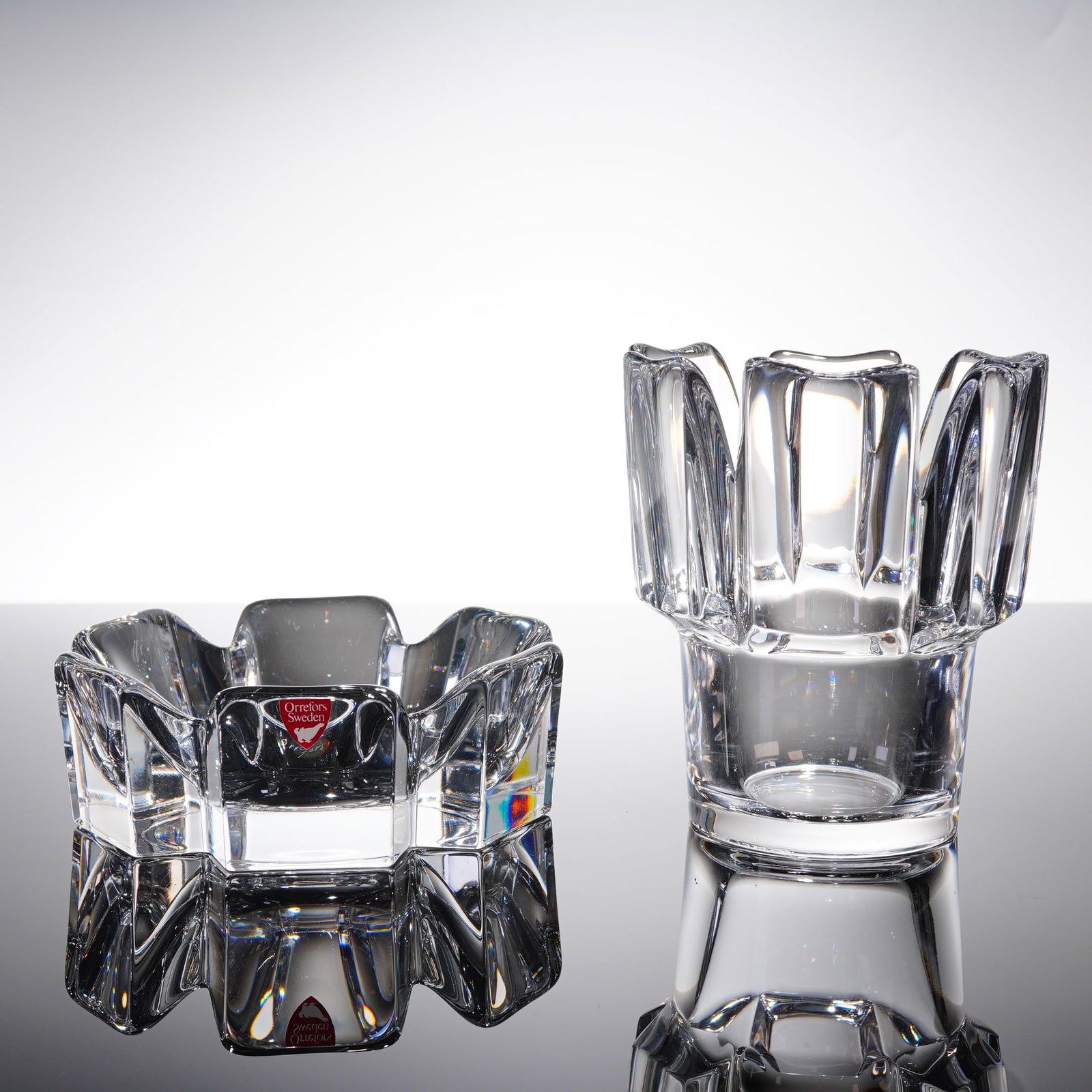 A Pair of Orrefors Swedish Crystal Dish and Vase: A pair of Swedish modernist crystal glass vessels by Orrefors, comprising two items. The first item is a squat, geometric dish featuring heavy faceting and thick walls, consistent with the Orrefors Co