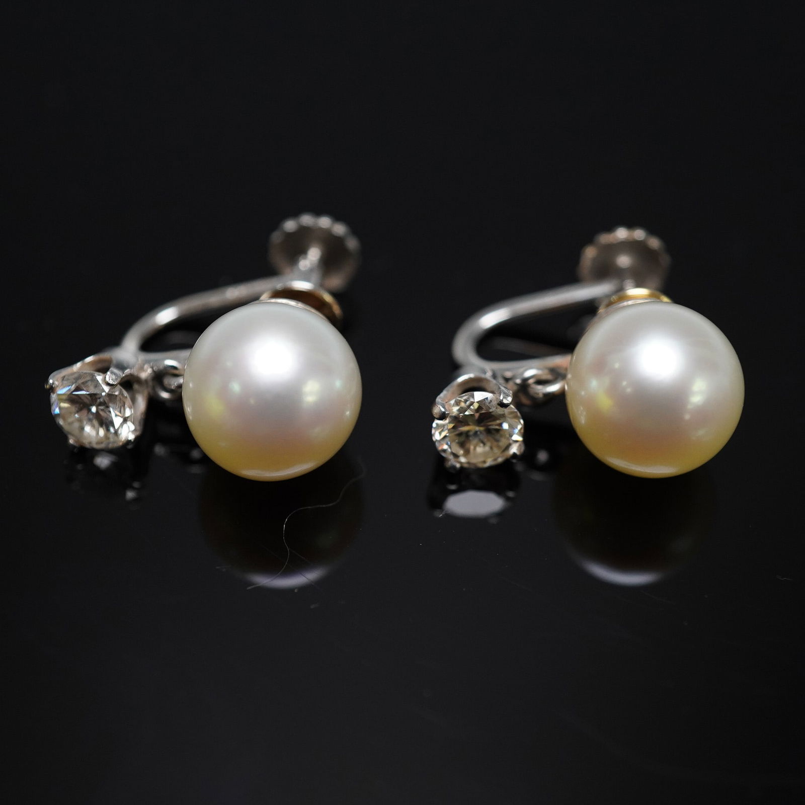 0.70CTW 14K Gold Pearl and Diamond Screwback Earrings: Elegant vintage earrings crafted in 14K white gold, each featuring a luminous cultured pearl suspended below a brilliant round-cut diamond weighing approximately 0.35ct. The diamonds are graded VS1 cl