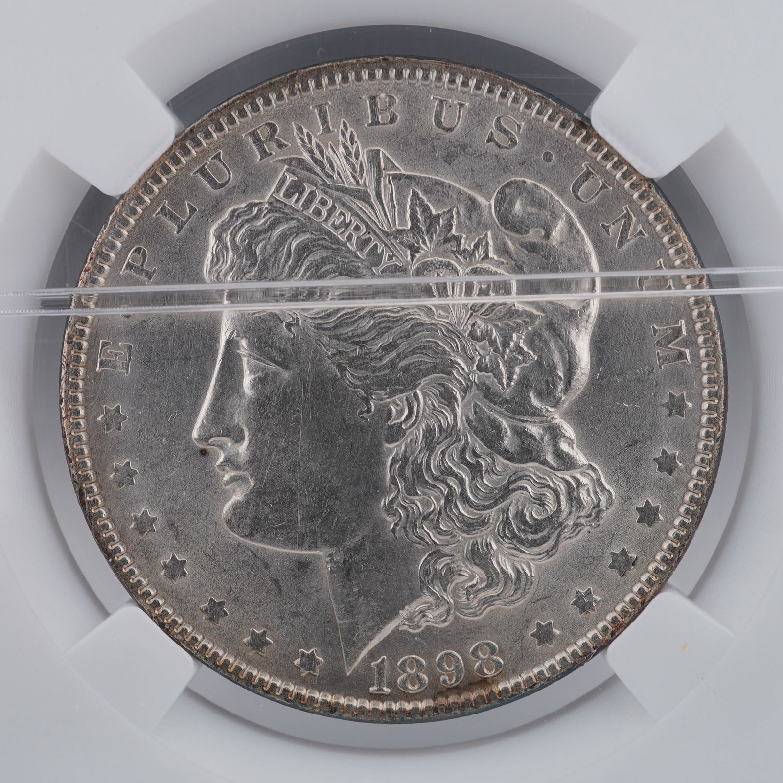 1898 Morgan Silver Dollar: Displayed is an 1898 Morgan Silver Dollar, composed of ninety percent silver. The obverse features George T. Morgan's classical representation of Liberty, adorned with a Phrygian cap and an agricultur