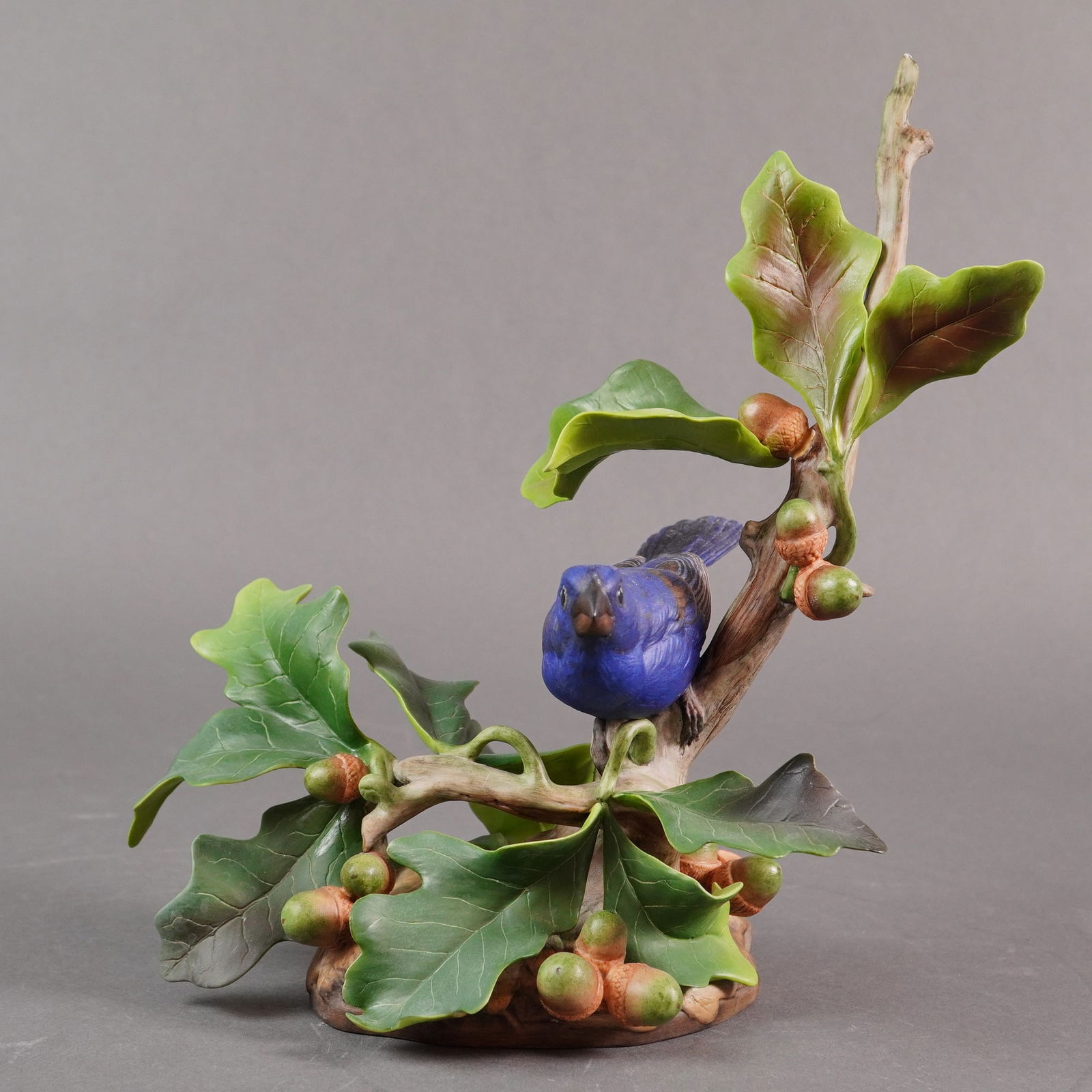 Boehm Porcelain Sculpture, Blue Grosbeak 489: A limited edition Boehm porcelain sculpture titled the Blue Grosbeak (Guiraca caerulea), Model 489. The male bird is represented with deep cobalt blue plumage, perched amidst the limbs of an oak branc