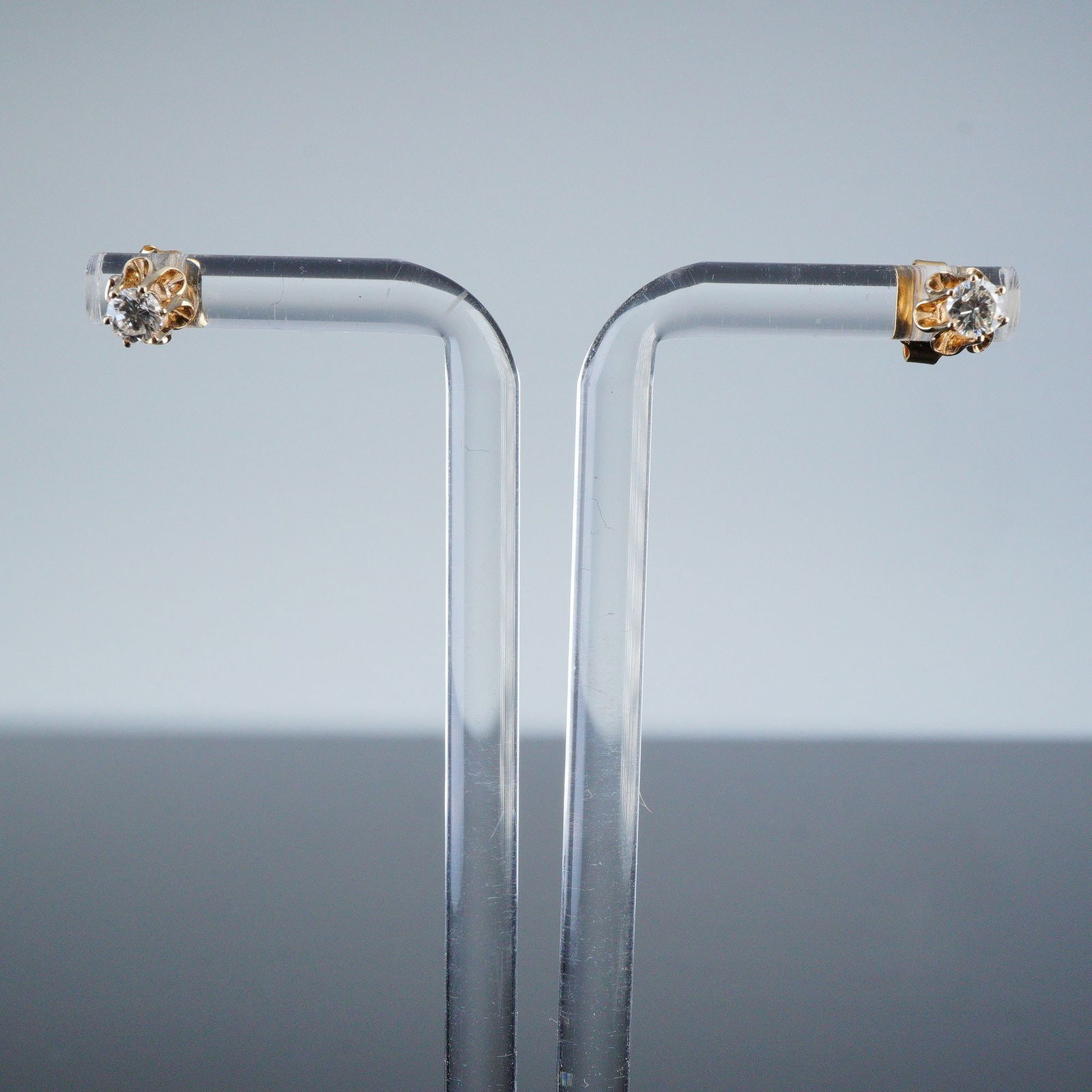 14K Yellow Gold Solitaire Diamond Stud Earrings: A pair of 14K yellow gold solitaire stud earrings. Each earring features a single round, brilliant-cut clear diamond secured in a four-prong setting. The earrings utilize a push-back post fastening sy