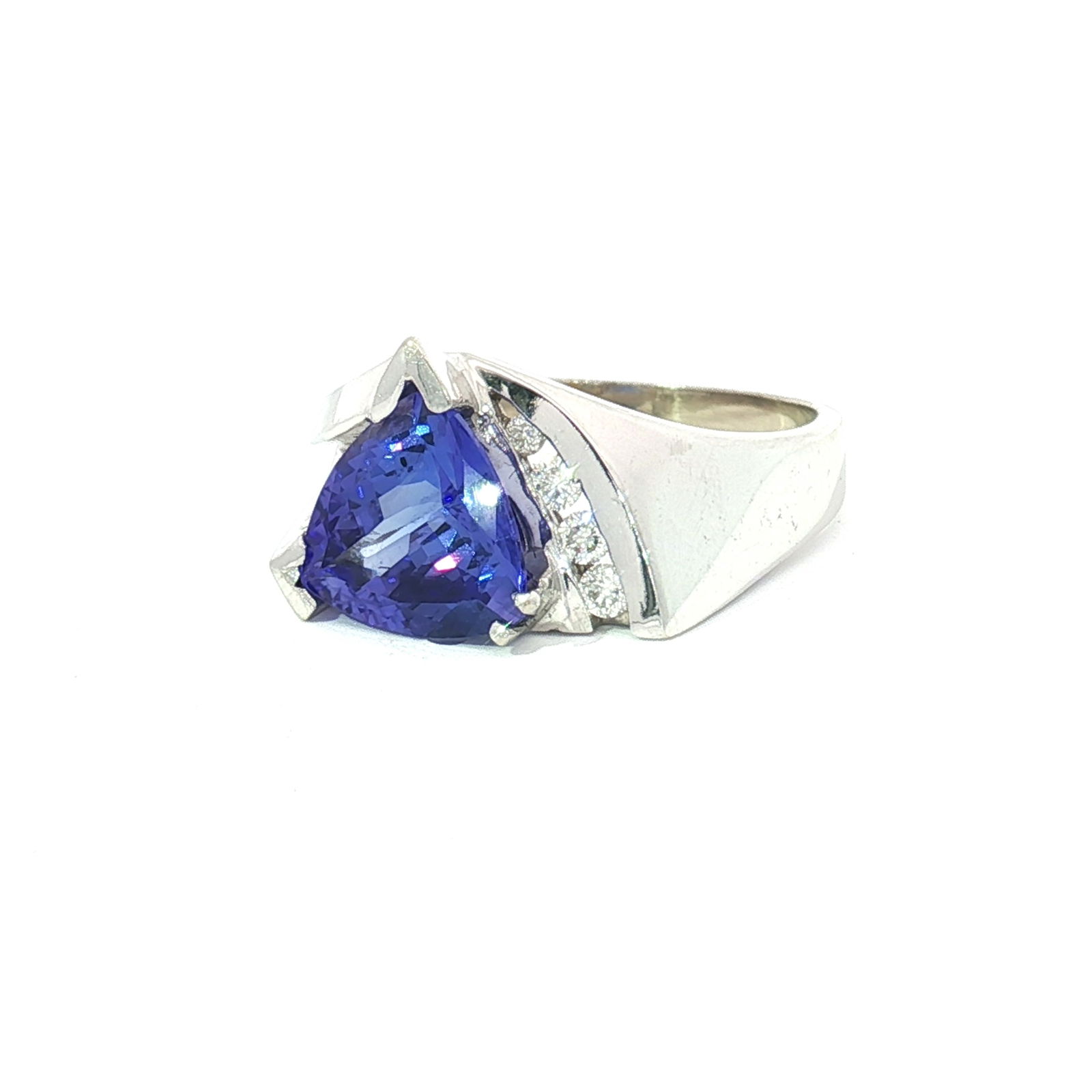 14K White Gold Trillion Cut Tanzanite and 0.15ctw Diamond Ring: This ring is crafted from 14k white gold and features a trillion cut Tranzanite stone. The central stone is accented by four small diamonds on one side. The diamonds have a combined total weight of ap