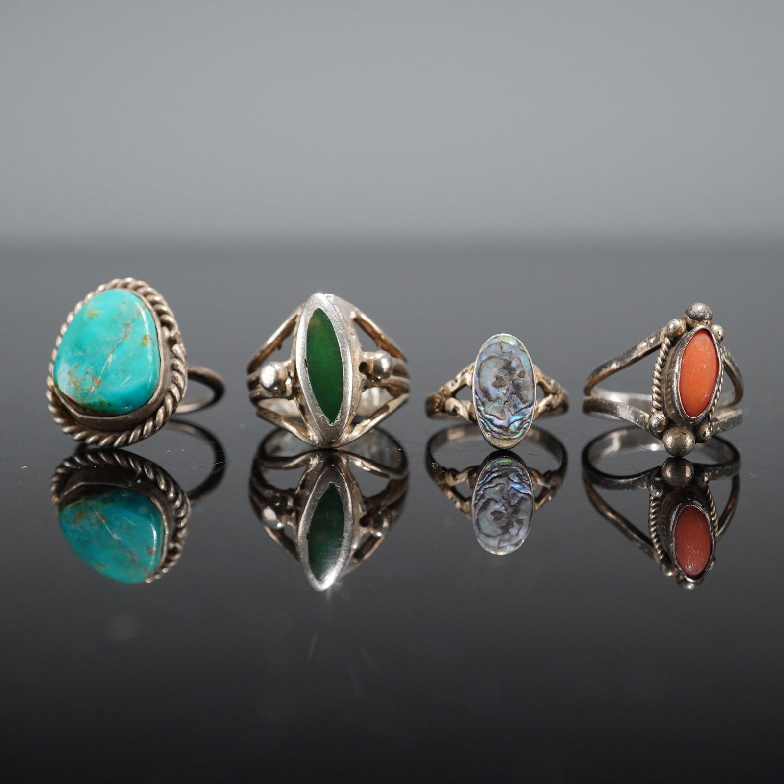 4pc Southwestern Style Silver Rings with Turquoise Coral and Abalone: A collection of four Southwestern/Native American finger rings crafted with the metal testing as sterling silver (.925), although no marks are visible. The collection includes four distinct cabochon s