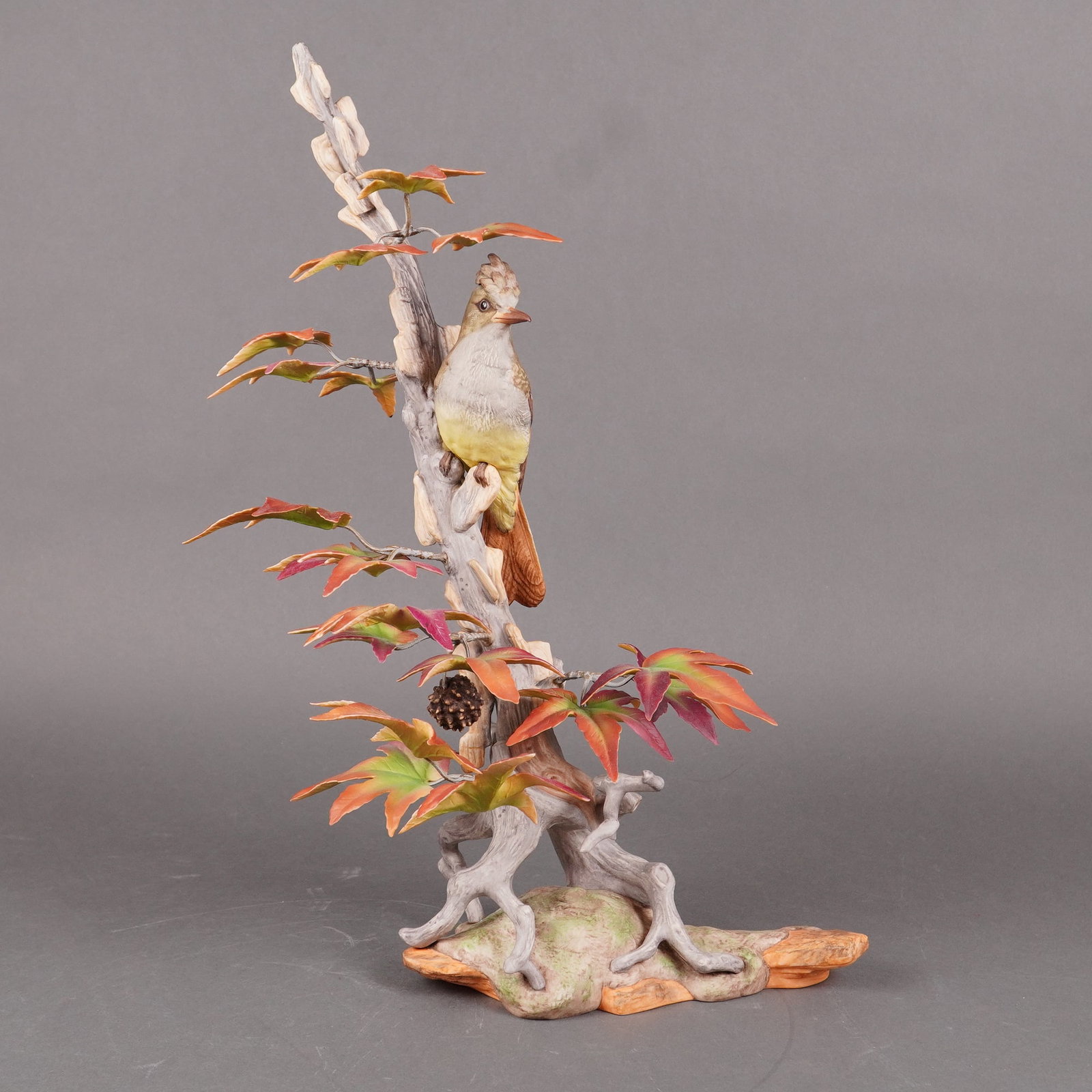 Boehm Porcelain Sculpture, Crested Flycatcher 488: A single Boehm USA limited edition porcelain figural sculpture titled Crested Flycatcher. The sculpture depicts the bird, detailed with yellowish-green and brown plumage, perched on a weathered gray t