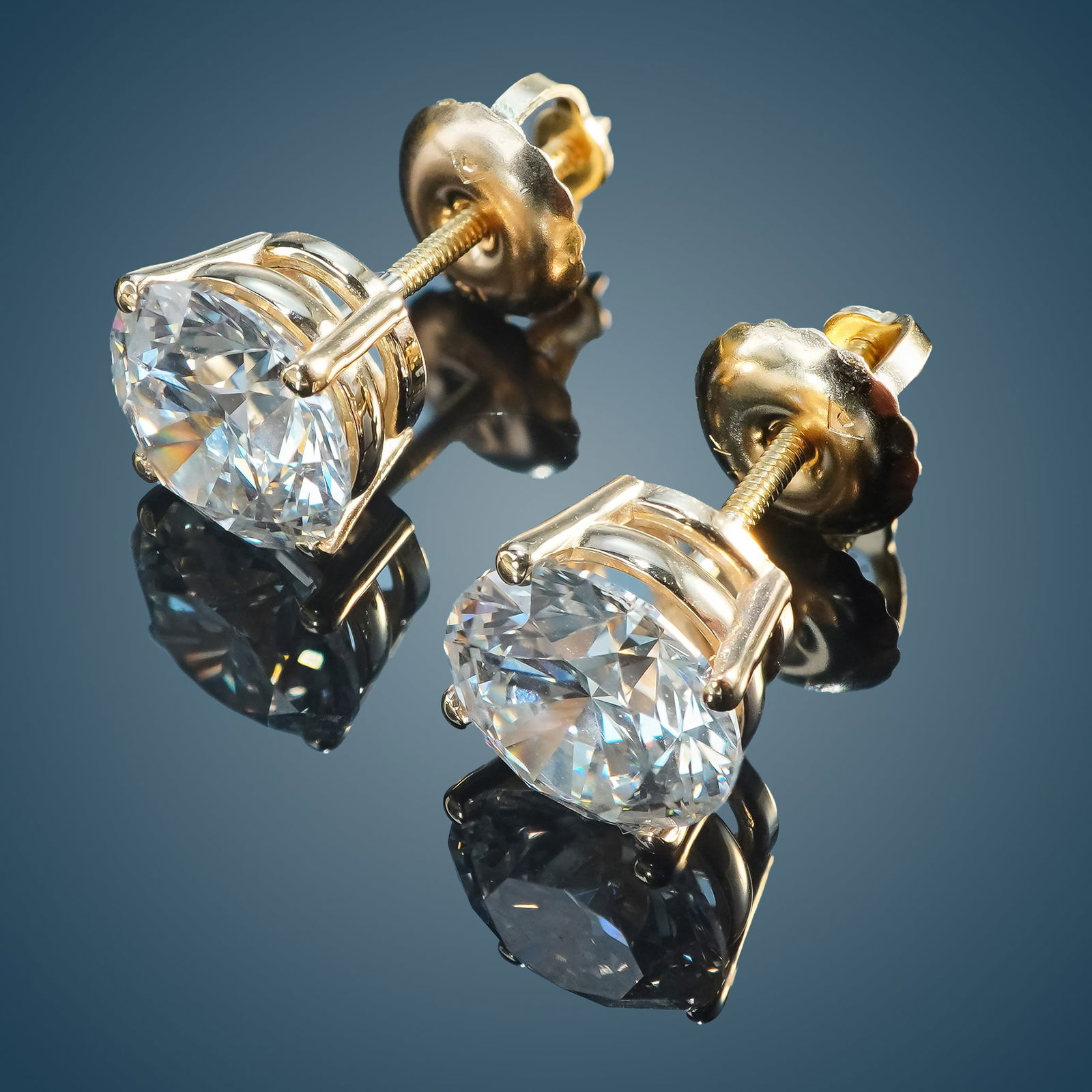 Pair of 14K Gold and 2.04ctw Diamond Stud Earrings: A pair of stud earrings crafted from 14K yellow gold, featuring a four-prong setting and screw-back design. Each prong holds a round, brilliant cut diamond with D color grade and VS1 clarity. The diam