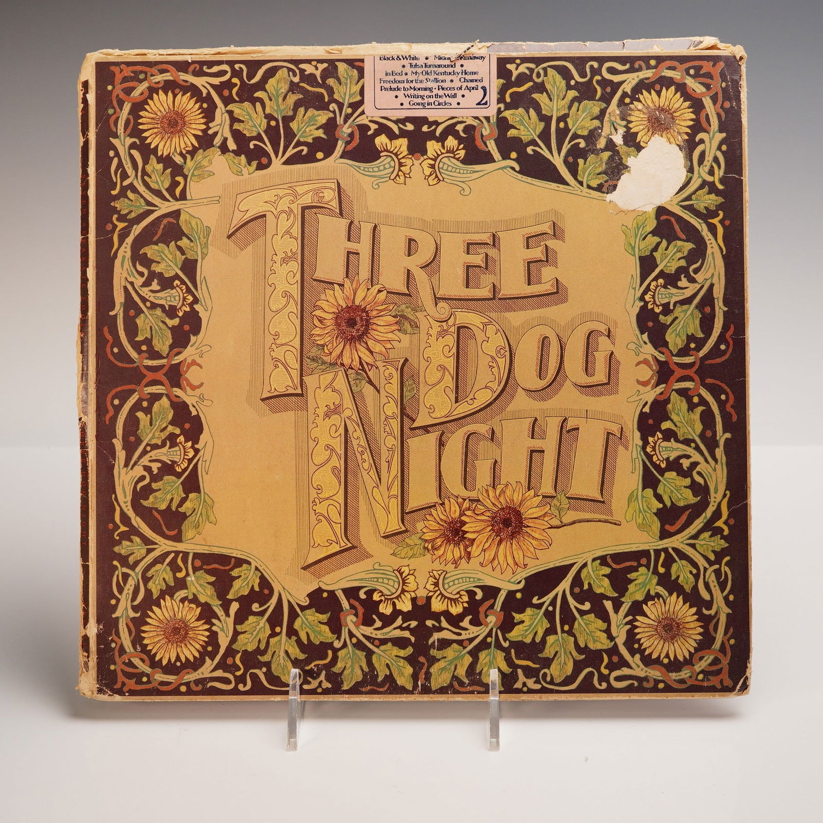 Three Dog Night Vinyl Record, Seven Separate Fools: A bold vinyl of Three Dog Night Seven Separate Fools, pressed on black vinyl with a classic black Dunhill label, featuring a richly detailed cover with golden lettering framed by floral motifs and sun