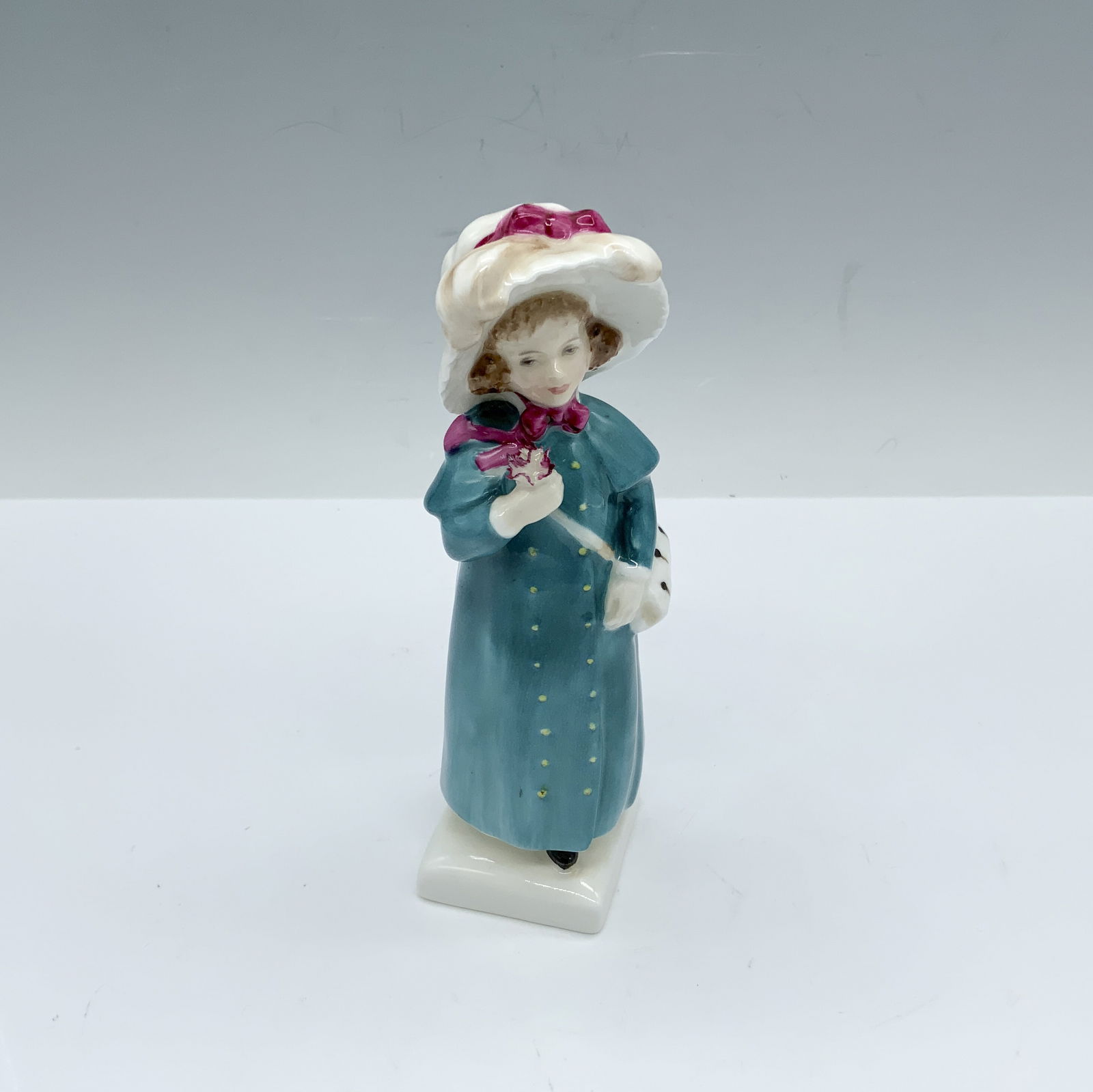 Carrie HN2800 - Royal Doulton Figurine: This girl in a turquoise dress figure from the Kate Greenaway Collection is based of one of Kate's books named Under The Window which contains idyllic verses concerning children who endlessly gathered