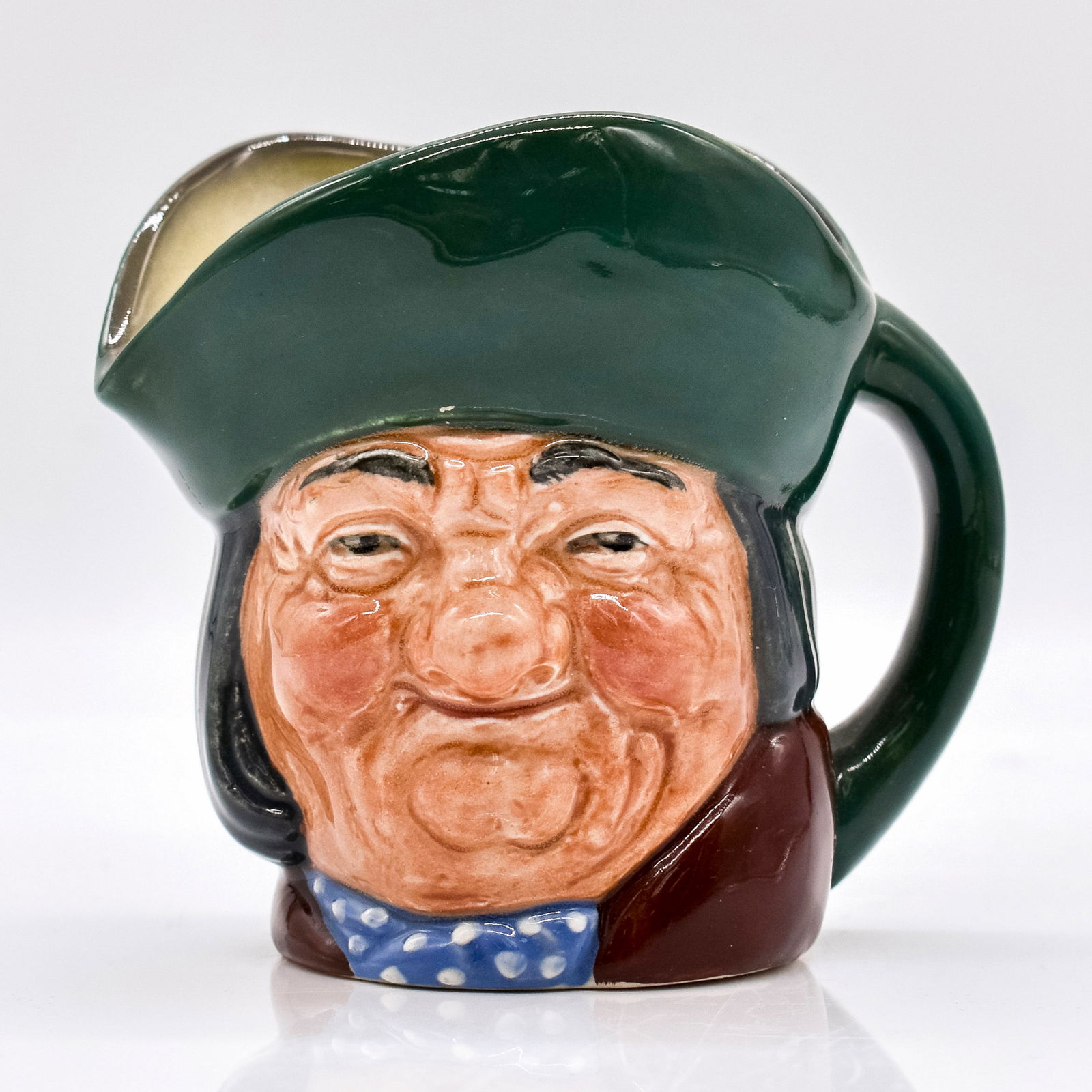 Toby Philpots D5737 - Small - Royal Doulton Character Jug: Green hat; brown coat; blue scarf with white spots. A "thirsty old soul" in an 18th century drinking song, Toby is thought by some to be the source of the traditional British toby jug, in which a char