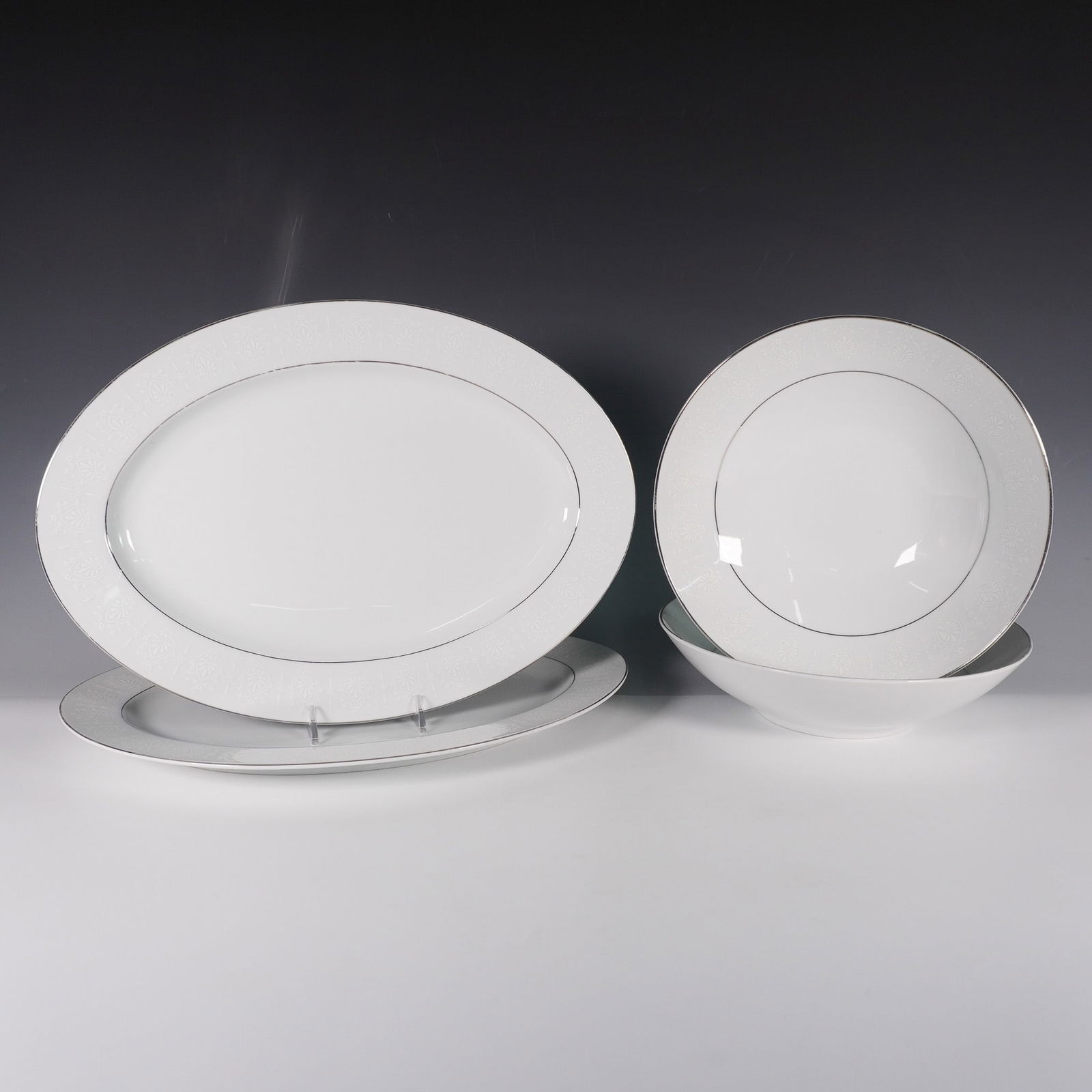 4pc Crown Empire Fine China Serving Trays and Bowls, Princess: Crown Empire fine china tableware set in the Princess pattern, featuring white floral and fleur-de-lis decorations with metallic-silver trim. This collection includes two round serving bowls and two o