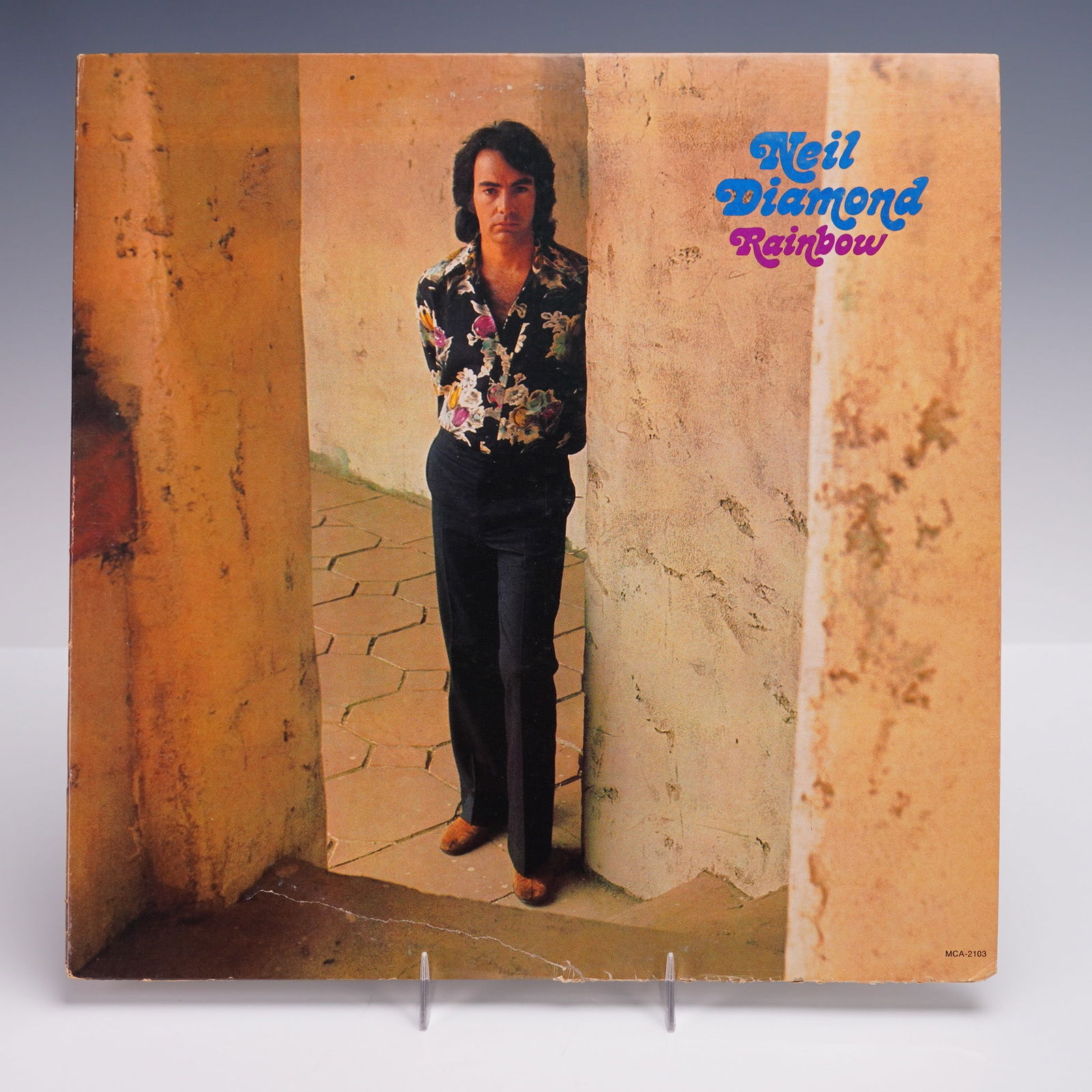 MCA Records Neil Diamond Vinyl Record, Rainbow: A 1973 U.S. reissue of Neil Diamond's "Rainbow" LP vinyl album, released by MCA Records. he front cover features a contemplative Neil Diamond posed within a weathered stucco corridor, while the revers