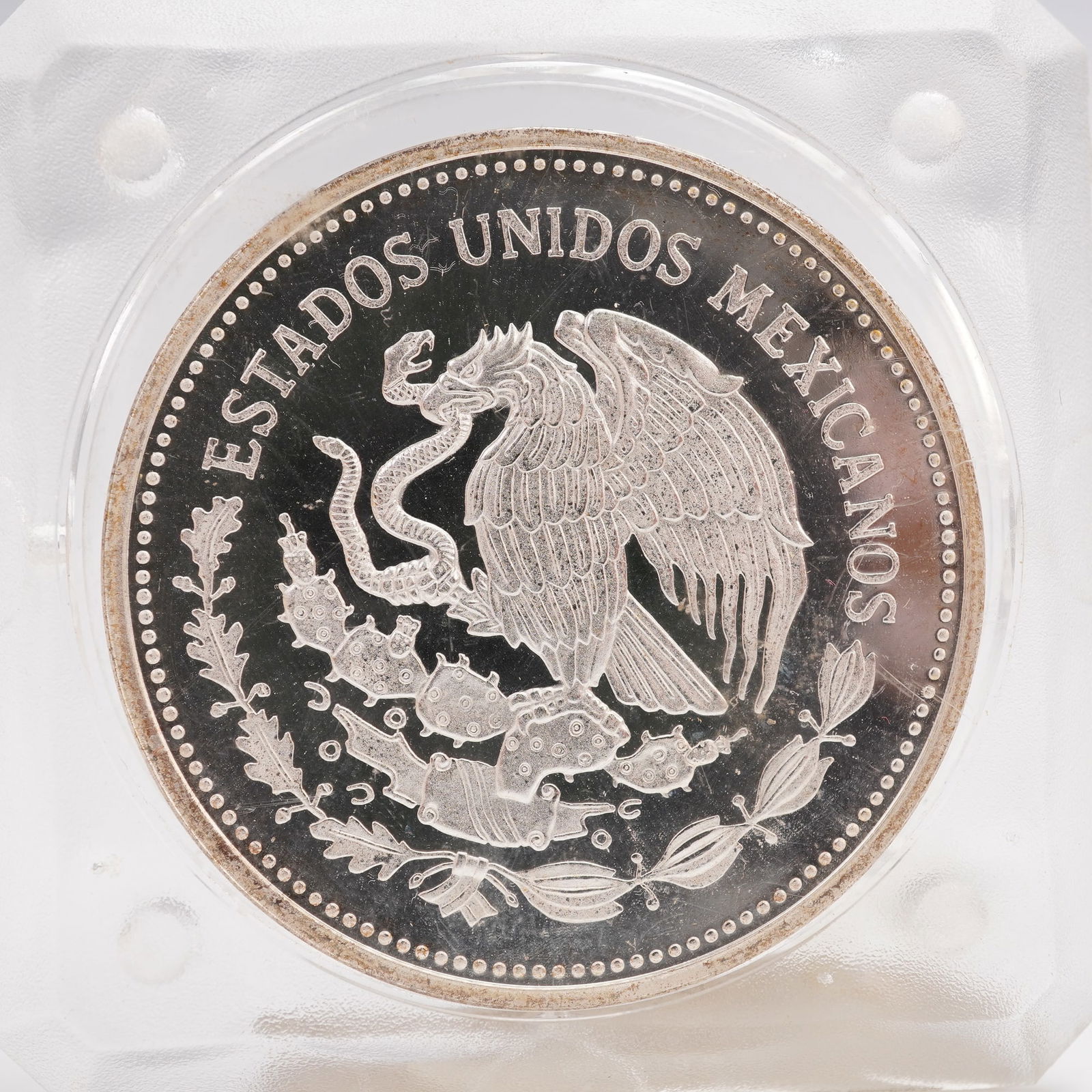 1985 FIFA World Cup Soccer 100 Peso 1oz Silver Coin: The obverse features the national coat of arms of Mexico with an eagle perched on a cactus devouring a snake, surrounded by a wreath and the inscription ESTADOS UNIDOS MEXICANOS. The reverse depicts a