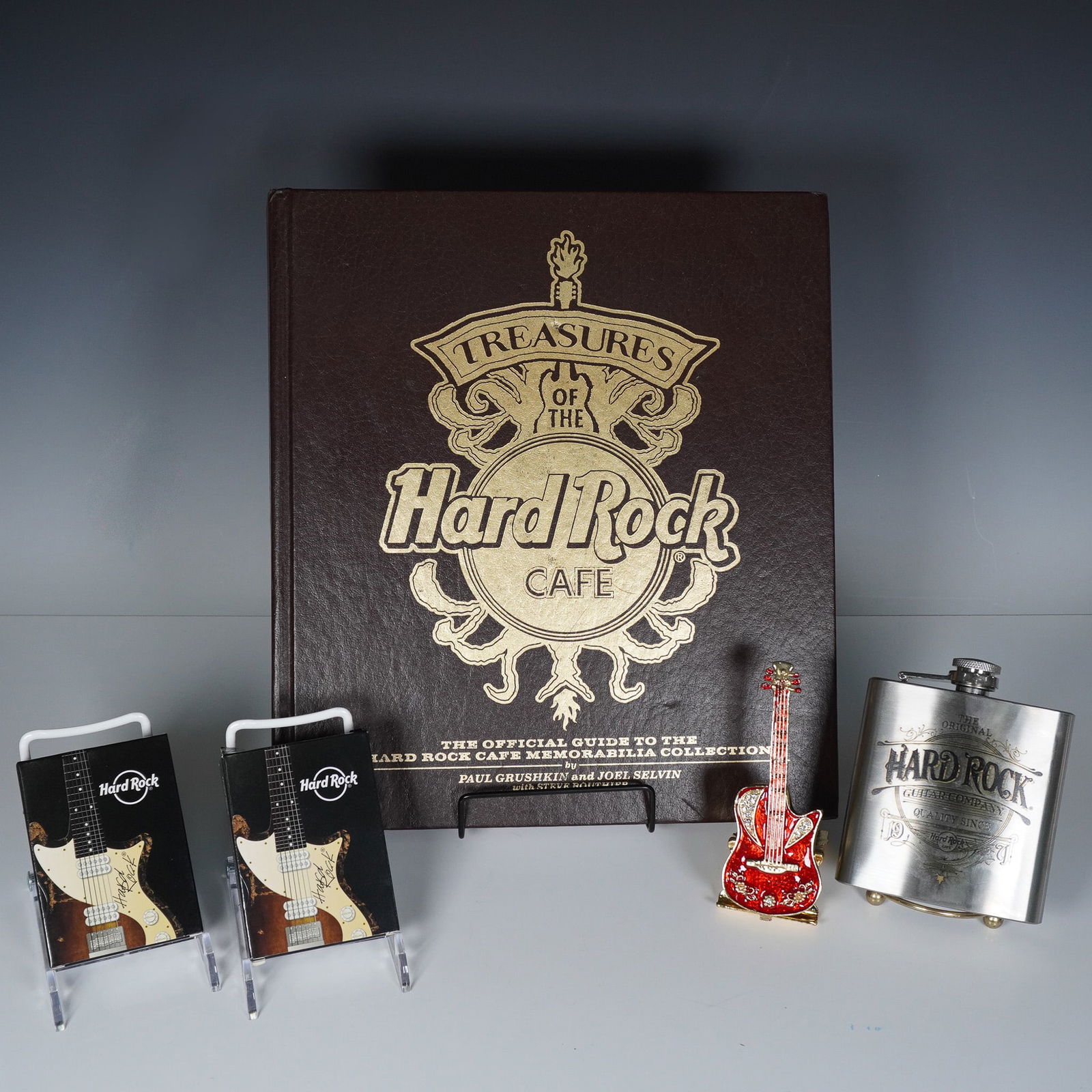 5pc Hard Rock Cafe Memorabilia Collection: A collection of five Hardrock collectibles including a copy of Treasures of the Hard Rock Cafe: The Official Guide to the Hard Rock Cafe Memorabilia Collection by Paul Grushkin and Joel Selvin, two se