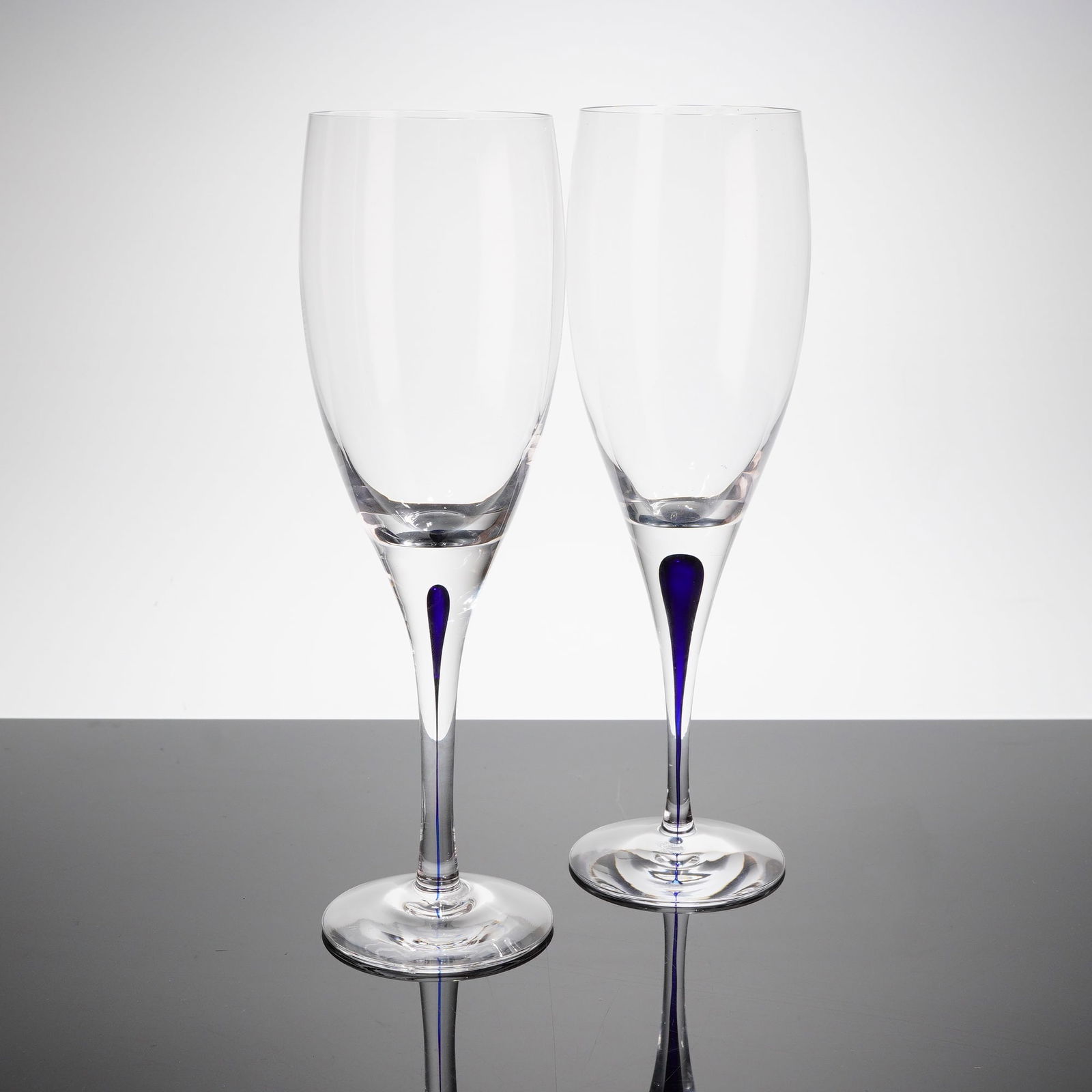 A Pair of Orrefors Intermezzo Claret Wine Glasses: A pair of Orrefors Intermezzo Blue Claret Wine Glasses, executed in clear transparent glass. This design, part of the Intermezzo patern, features a smooth, undecorated bowl supported by a tall stem. T