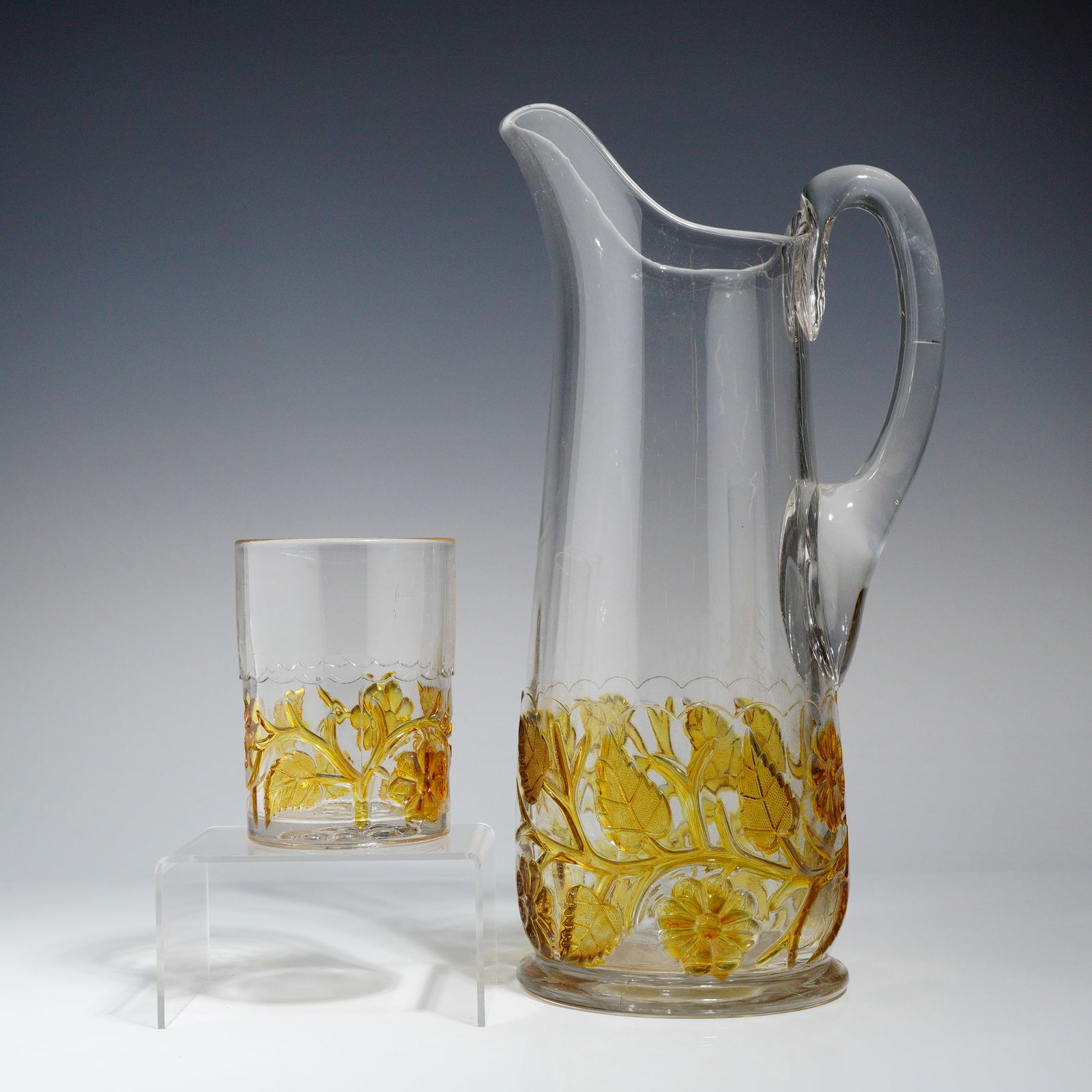 Hobbs EAPG Amber Water Pitcher and Tumbler: A two-piece set of Early American Pressed Glass (EAPG) attributed to Hobbs Brockunier Glass Co., circa 1890s, in the "Leaf & Flower" pattern. The set includes a tankard water pitcher and an accompanyi