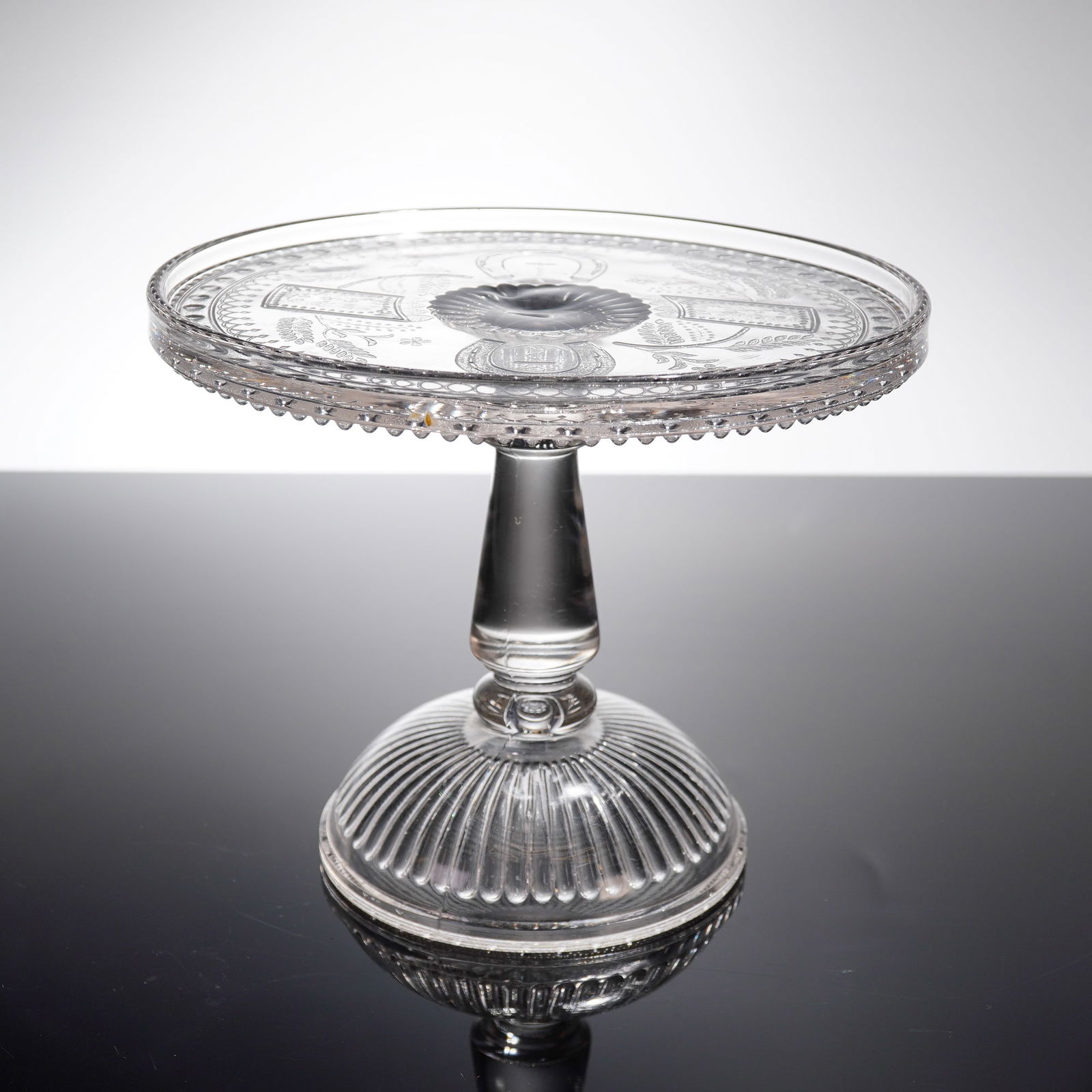 Adams & Company Good Luck Horseshoe Pedestal Cake Stand: A single Early American pressed glass (EAPG) pedestal cake stand, identified as the "Good Luck" pattern, also known as "Prayer Rug," manufactured by Adams & Company circa 1881. This footed compote dis