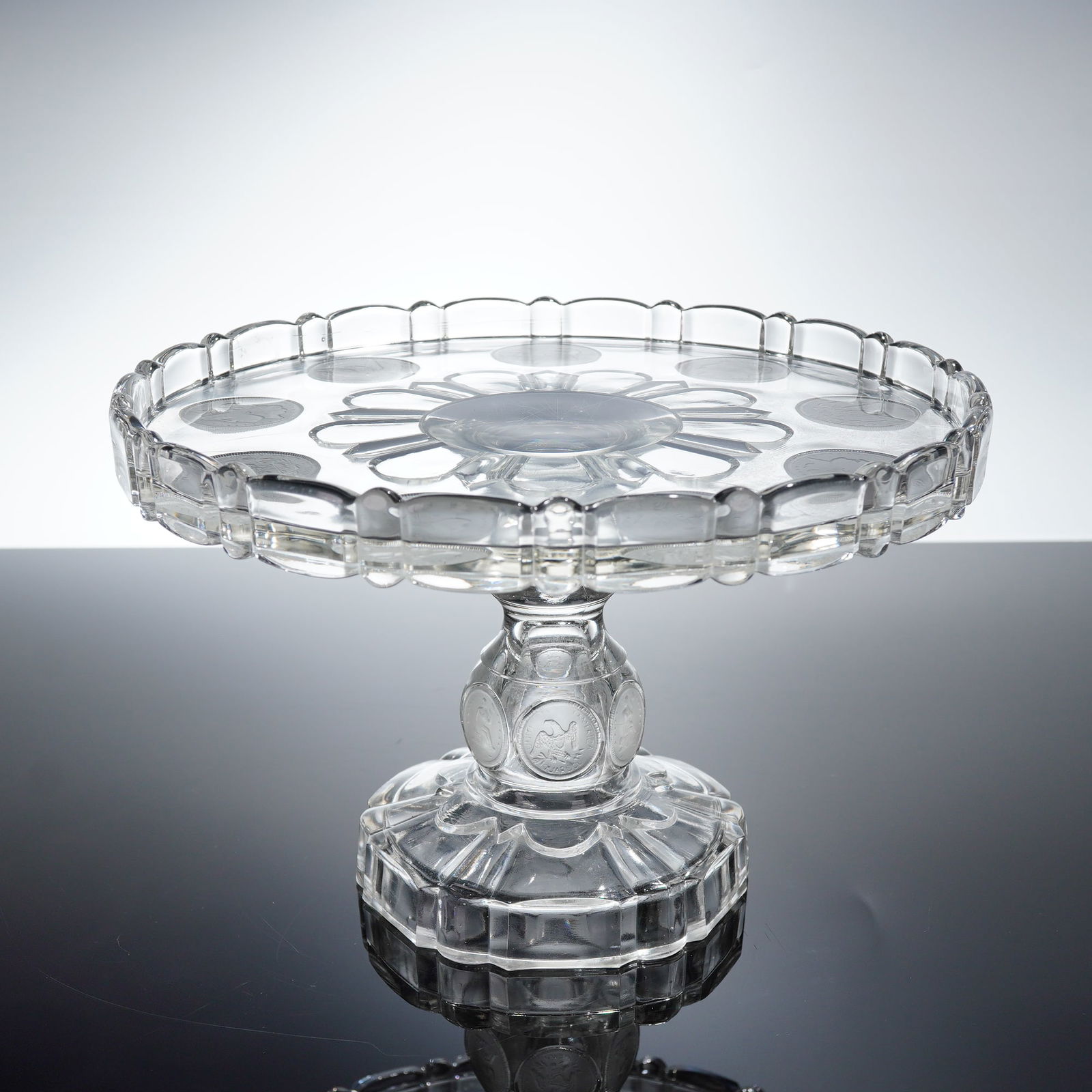 Central Glass Co. EAPG U.S. Coin Pattern Cake Stand: A single Early American Pressed Glass (EAPG) cake stand, attributed to the Central Glass Company, featuring the highly recognizable U.S. Coin or Silver Age pattern, circa 1892. The clear pressed glass