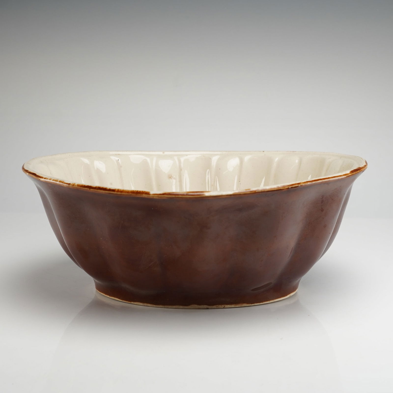 Ceramic Pudding Mold with Grape Relief: This is a vintage ceramic pudding mold is formed as a deep, lobed bowl, typical of Jello or Pudding Pottery Molds. The exterior is finished in a rich, glossy dark brown glaze. The interior features a