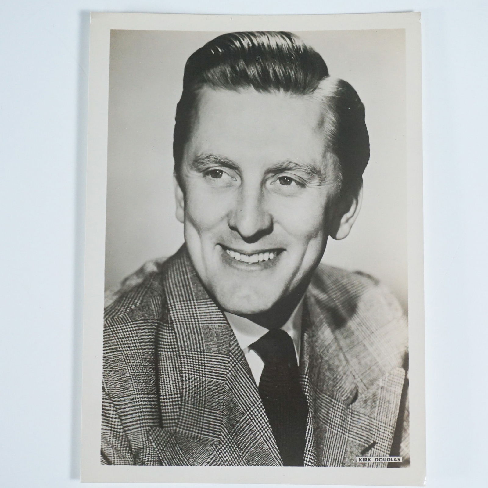 Kirk Douglas Vintage Promotional Photograph: Vintage black-and-white promotional photograph of Kirk Douglas, the legendary actor known for his powerful performances in classic films such as Spartacus, Paths of Glory, and Champion. This striking