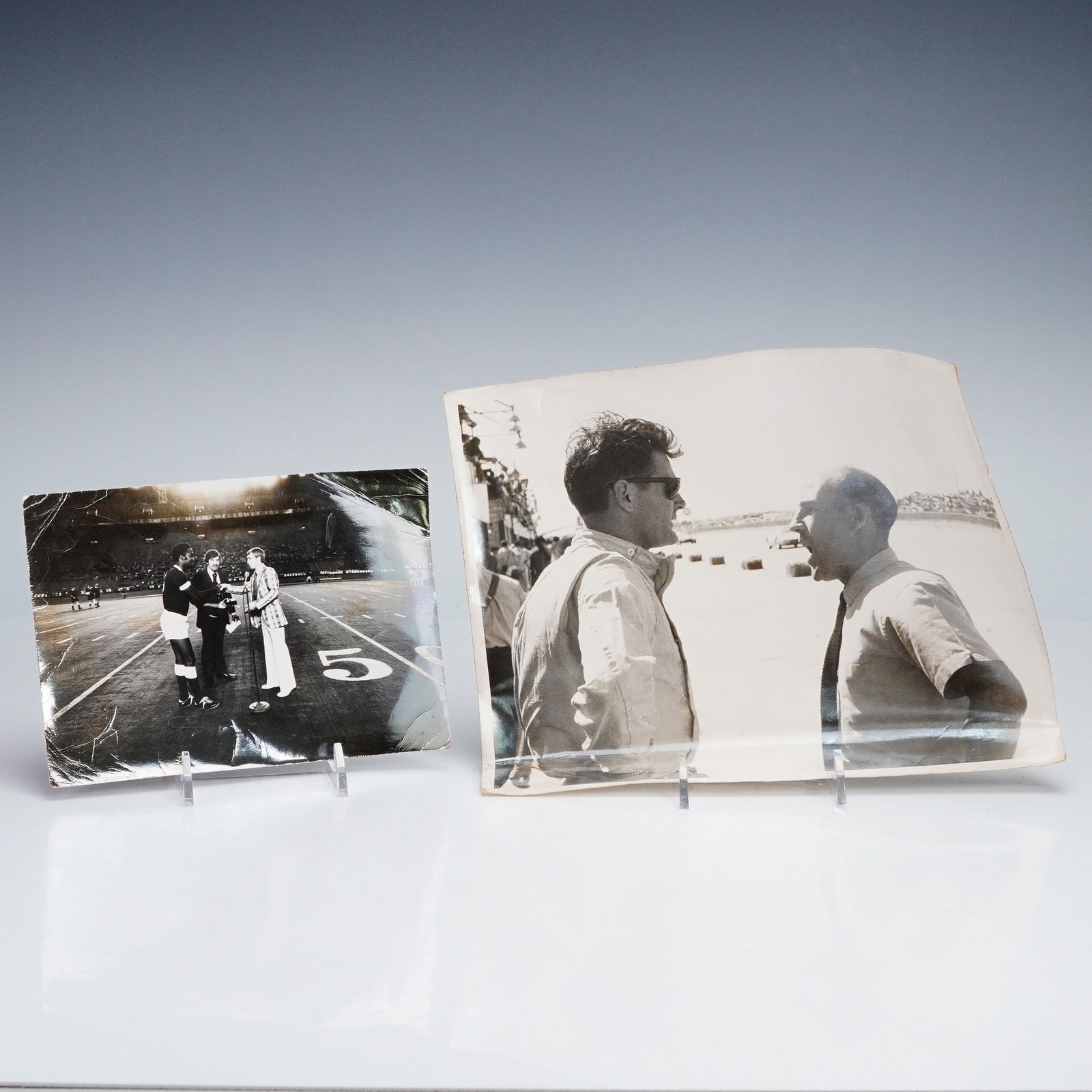 Pair of Vintage Press Photographs- Mario Andretti and Pele: A pair of vintage black and white press photographs depicting two iconic figures from the world of sports. The first shows legendary race car driver Mario Andretti, likely at the Indianapolis 500, in