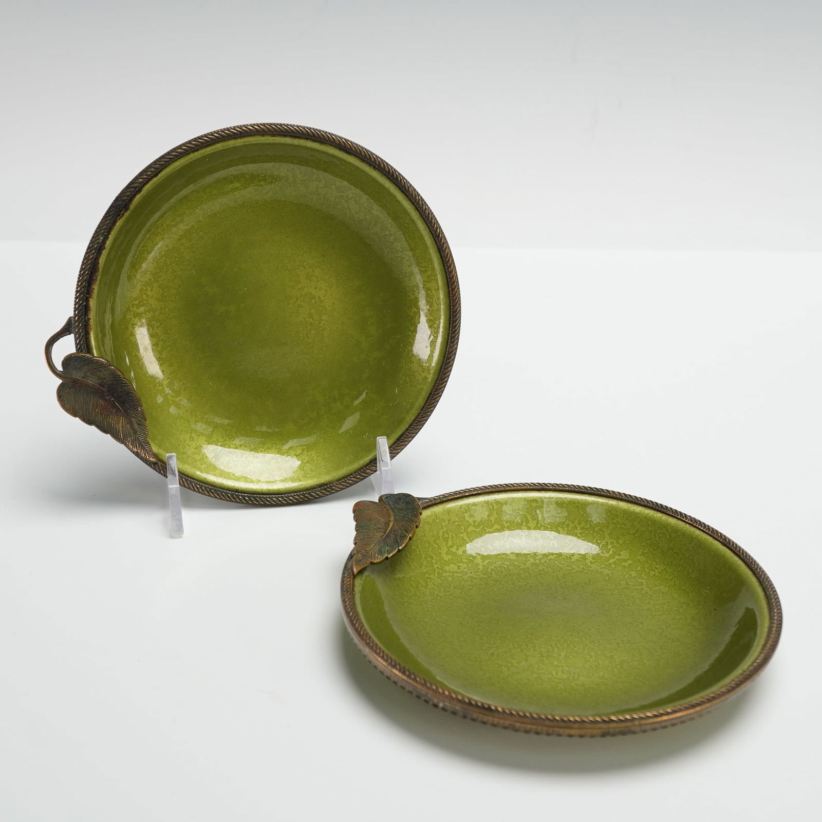 Pair of Evans Hand Enameled Ring/Coin Dishes with Braided Leaf Design: Each dish features a rich olive green enamel finish over metal with a braided rope edge and sculpted leaf accent. Marked on the underside with the Evans crest and Hand Enameled stamp. Likely mid 20th