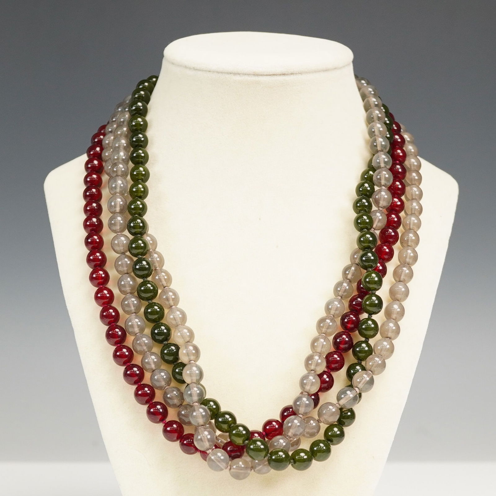 Multistrand Red, Green, and Smoky Bead Necklace: Striking triple-strand necklace featuring round beads in deep red, olive green, and smoky gray tones, arranged in alternating graduated rows. Each strand is securely gathered into a floral-inspired go