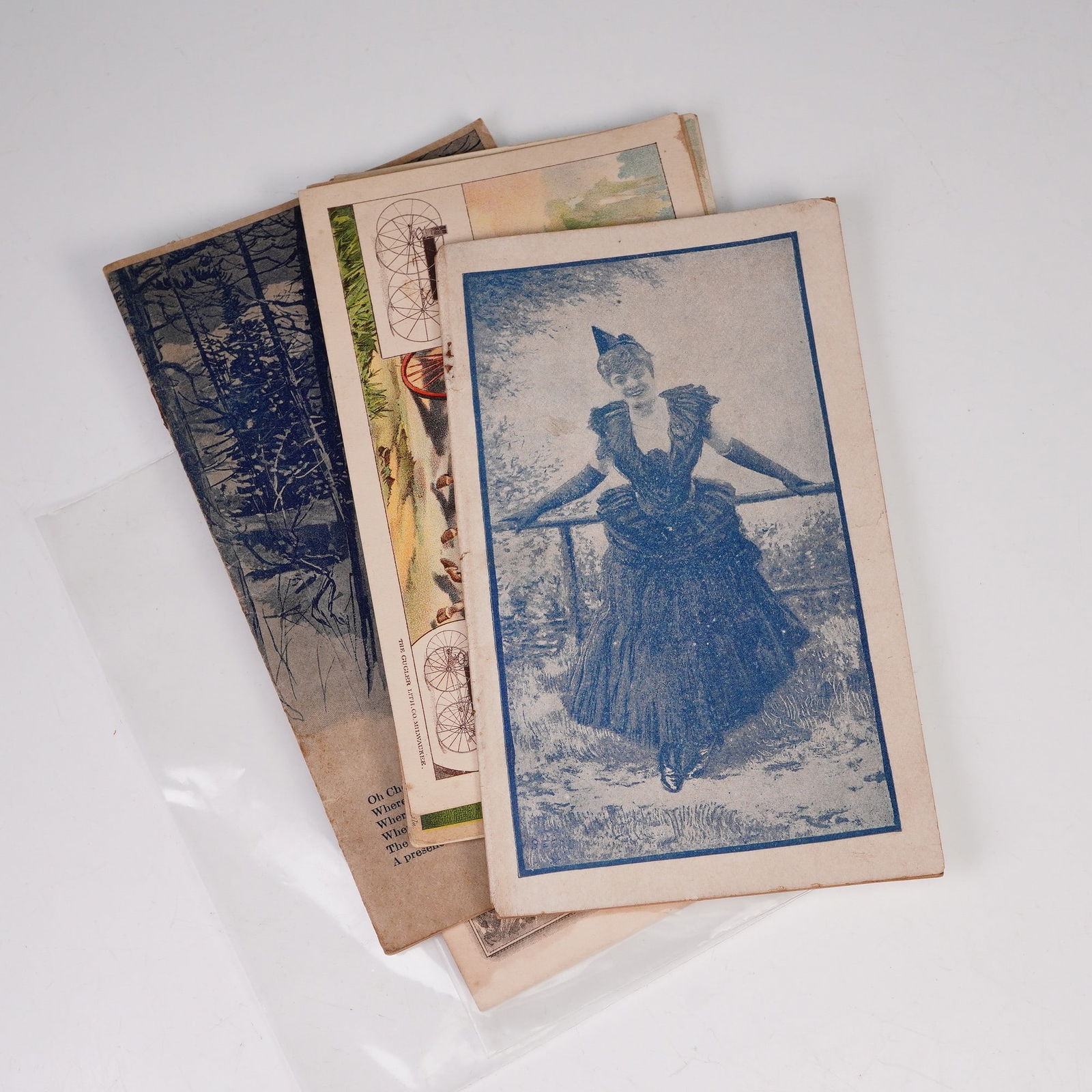 6pc Assorted Antique Advertisement Cards and Booklets: Advertisement cards and booklets including a blue-toned pill print featuring a woman in period dress, an illustrated booklet titled "In South Cheyenne Canon With Pen and Camera," a trade card for The