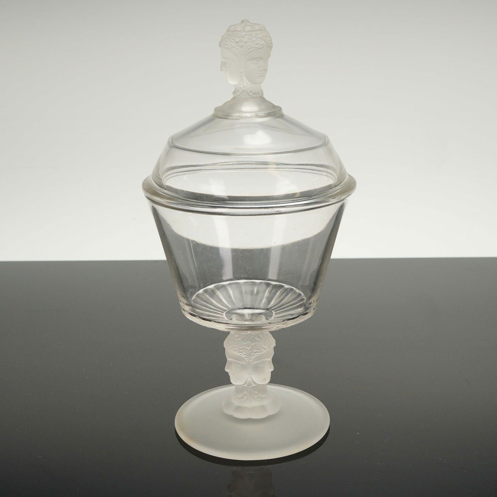 Duncan & Miller Three Faces Pressed Glass Covered Compote: A single covered compote executed in the Duncan & Miller "Three Faces" pressed glass pattern, characteristic of the Art Deco period. The piece is constructed from clear glass for the bowl and