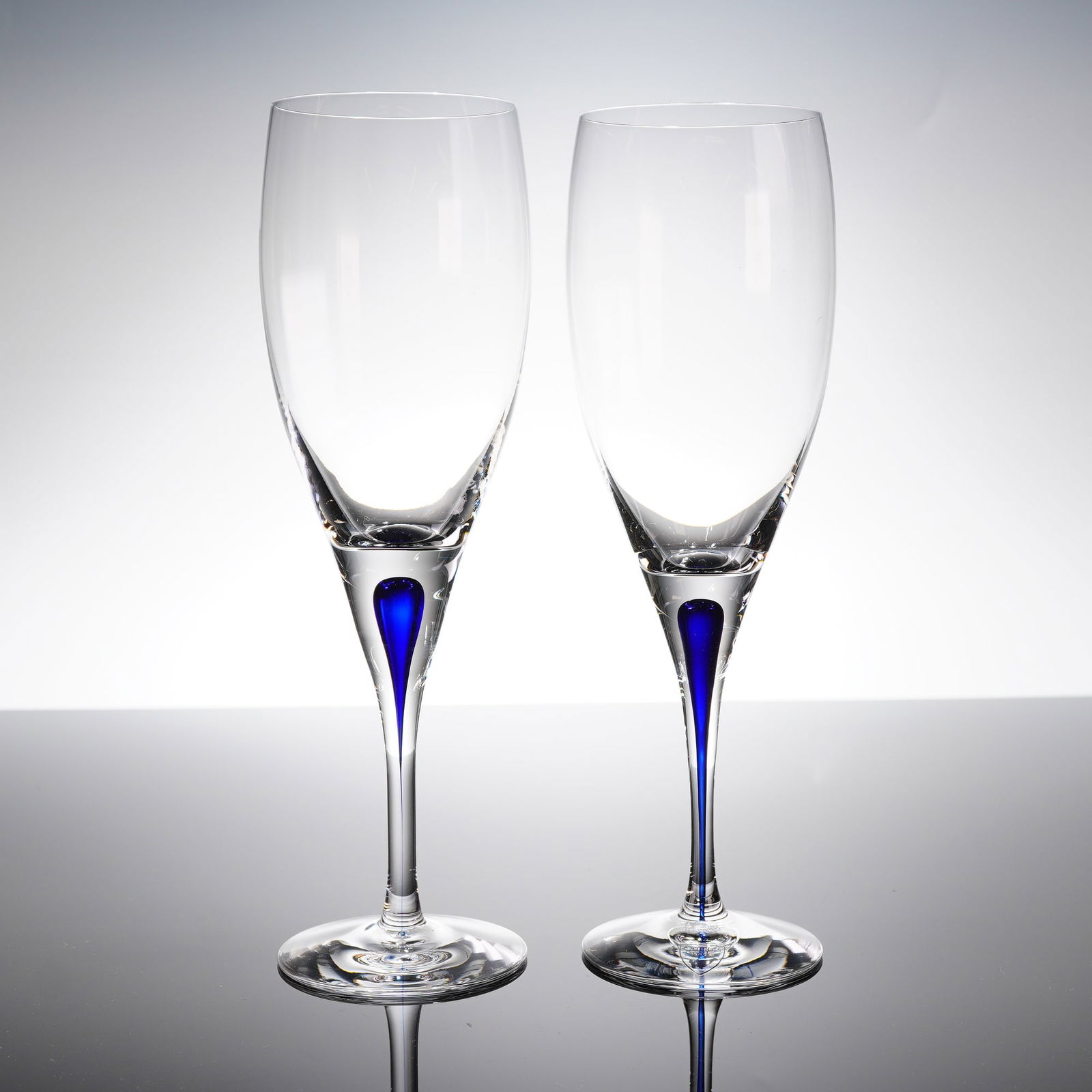 A Pair of Orrefors Intermezzo Crystal Champagne Flutes: A Pair of Orrefors Intermezzo Blue crystal champagne flutes. The Intermezzo patern is characterized by its clear crystal construction and a distinctive integrated internal teardrop accent of brilliant