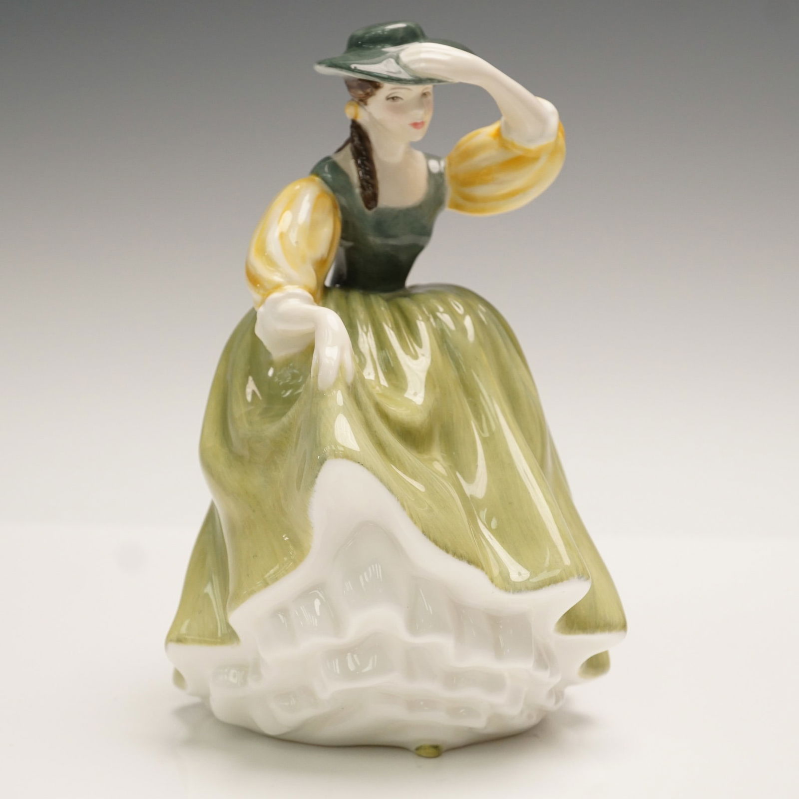 Royal Doulton Figurine, Buttercup HN2309: Part of the Peggy Davies Classics series. Modeled in a beautiful green dress with yellow sleeves. Royal Doulton backstamp. Artist: Peggy Davies Issued: 1964 - 1997 Dimensions: 4.25"L x 4.5"W x 7.5"H C