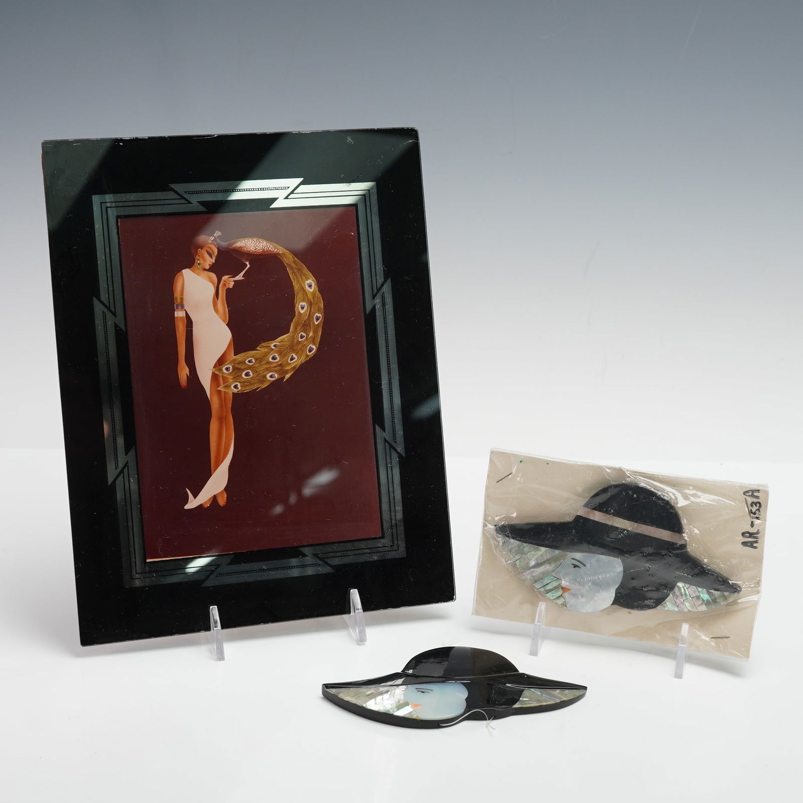 3pc Art Deco Style Framed Print and Lady with Hat Inlaid Brooches: Group of three Art Deco-inspired pieces, including one framed print depicting a glamorous woman in a white gown with a golden peacock-feather crescent, framed in a black mirrored border with geometric