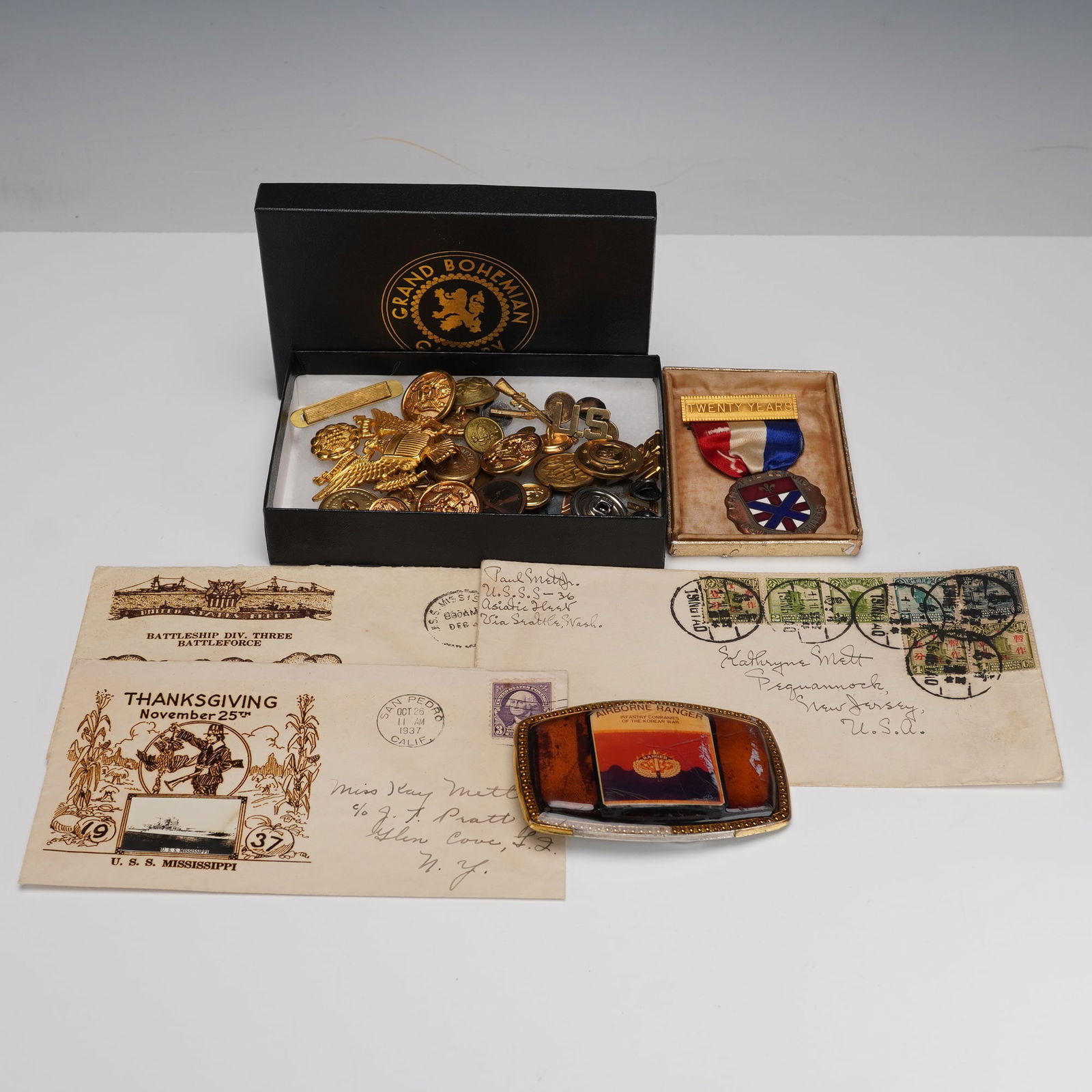 Assorted Military Memorabilia and Ephemera Collection: A varied collection of early to mid-20th century military-related treasures, including a selection of uniform buttons, insignia, and medals housed in a Grand Bohemian box, along with two vintage naval