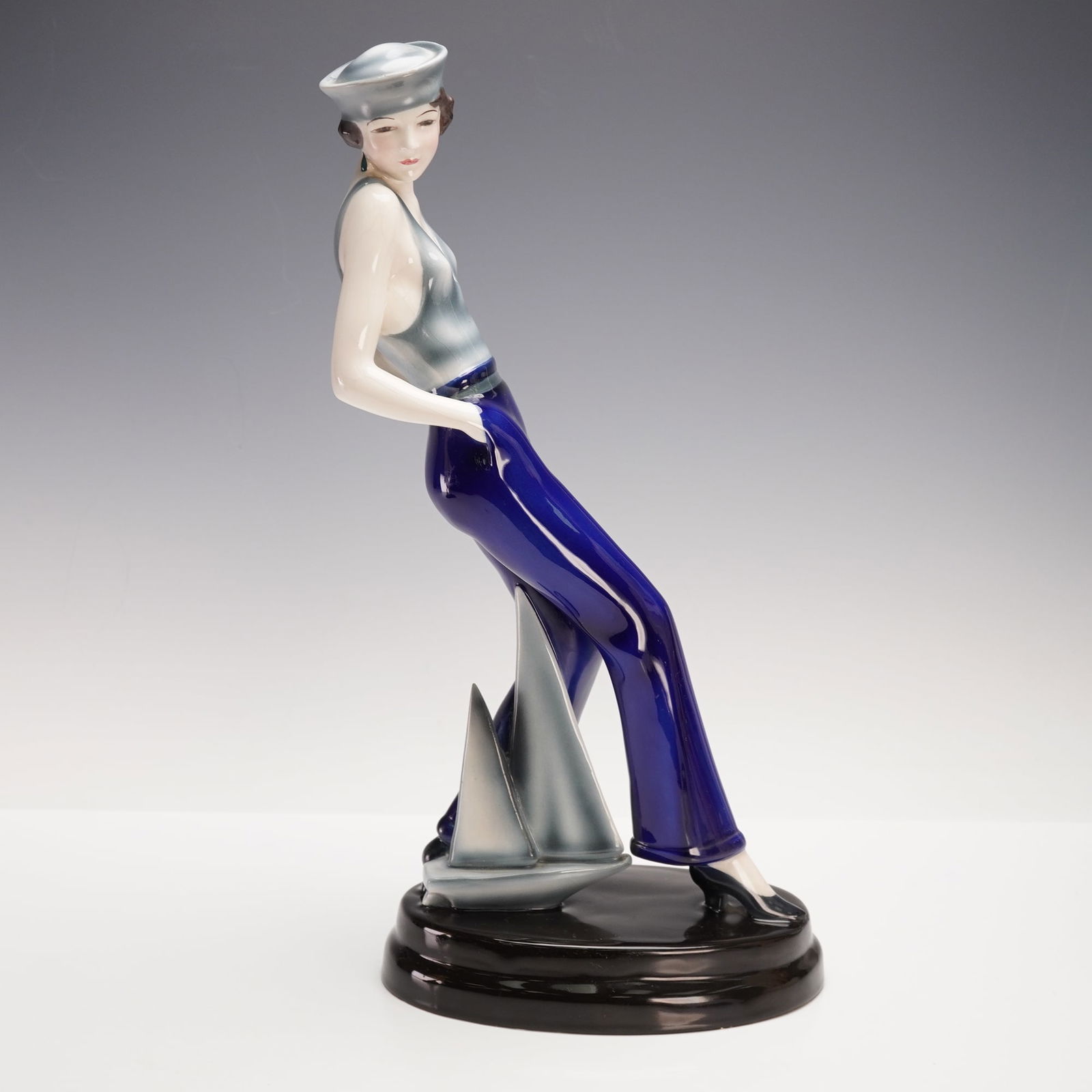 Goldscheider Colorway Sculpture, The Sailor Girl: Hand-decorated Goldscheider figurine, The Sailor Girl 5818, featuring a striking variation of glaze with blue pants, gray shirt and hat, and green earrings. The piece depicts a poised young woman in n
