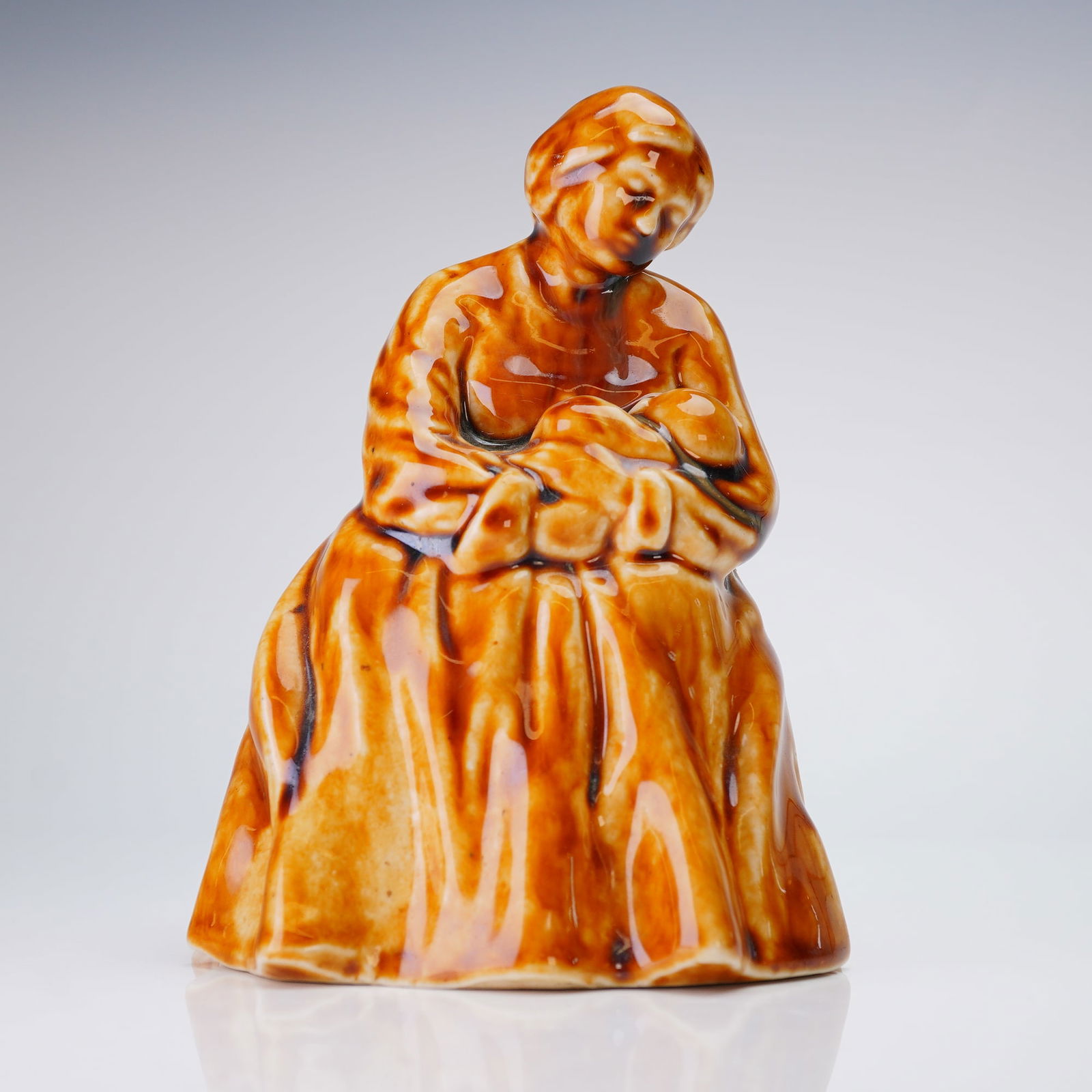 Royal Doulton by Leslie Harradine Stoneware Figurine, Motherhood H4: Rare early 20th century salt-glazed figurine designed by Leslie Harradine, depicting a seated mother nursing and cradling an infant. Finished in brown glaze. Painter's monogram "EW" on the underside,