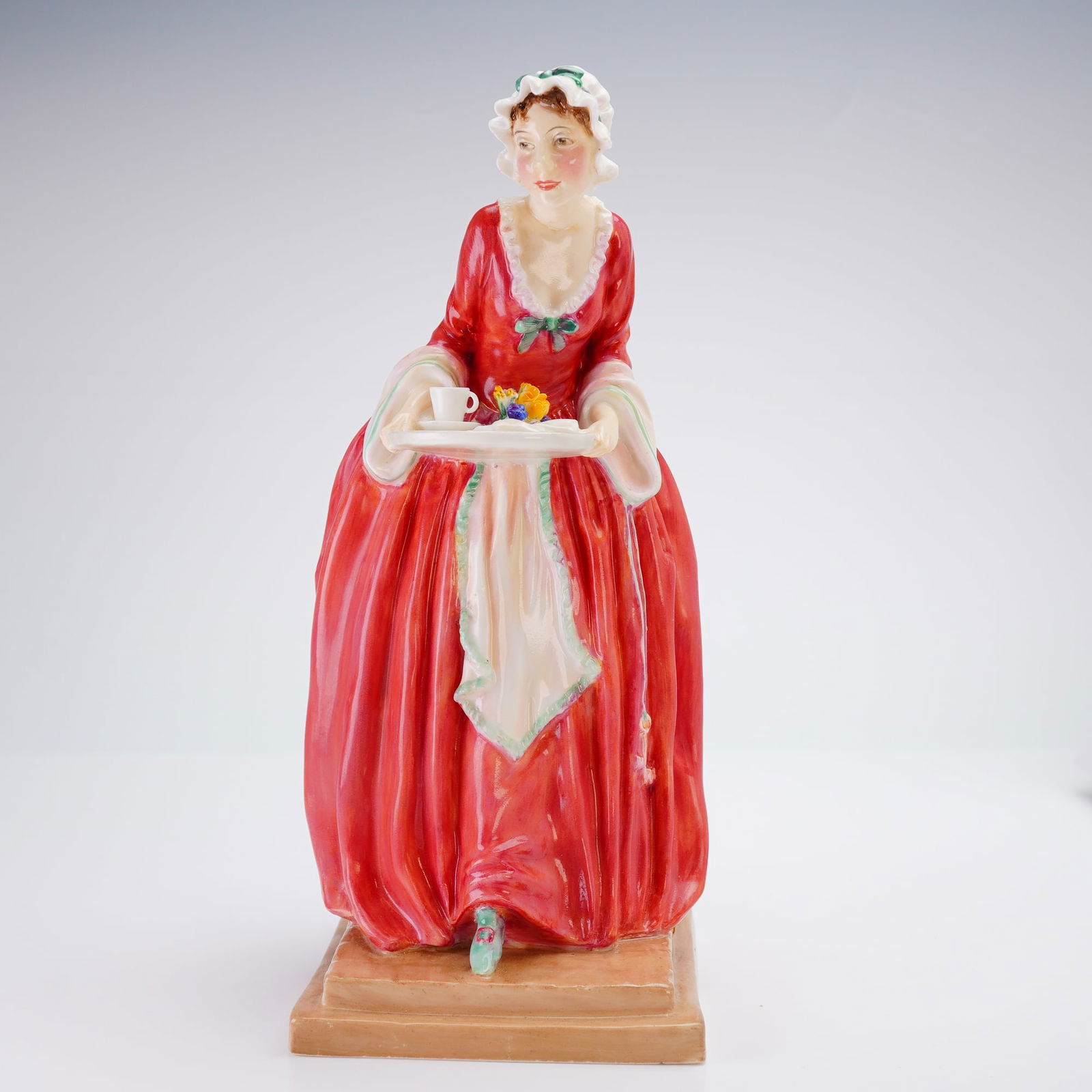 Royal Doulton Figurine, M'Lady's Maid HN1795: Royal Doulton M'Lady's Maid HN1795 porcelain figurine. This porcelain figure is modeled in 18th-century style attire, featuring a red gown with white trim, a white apron with green edging, and a ruffl