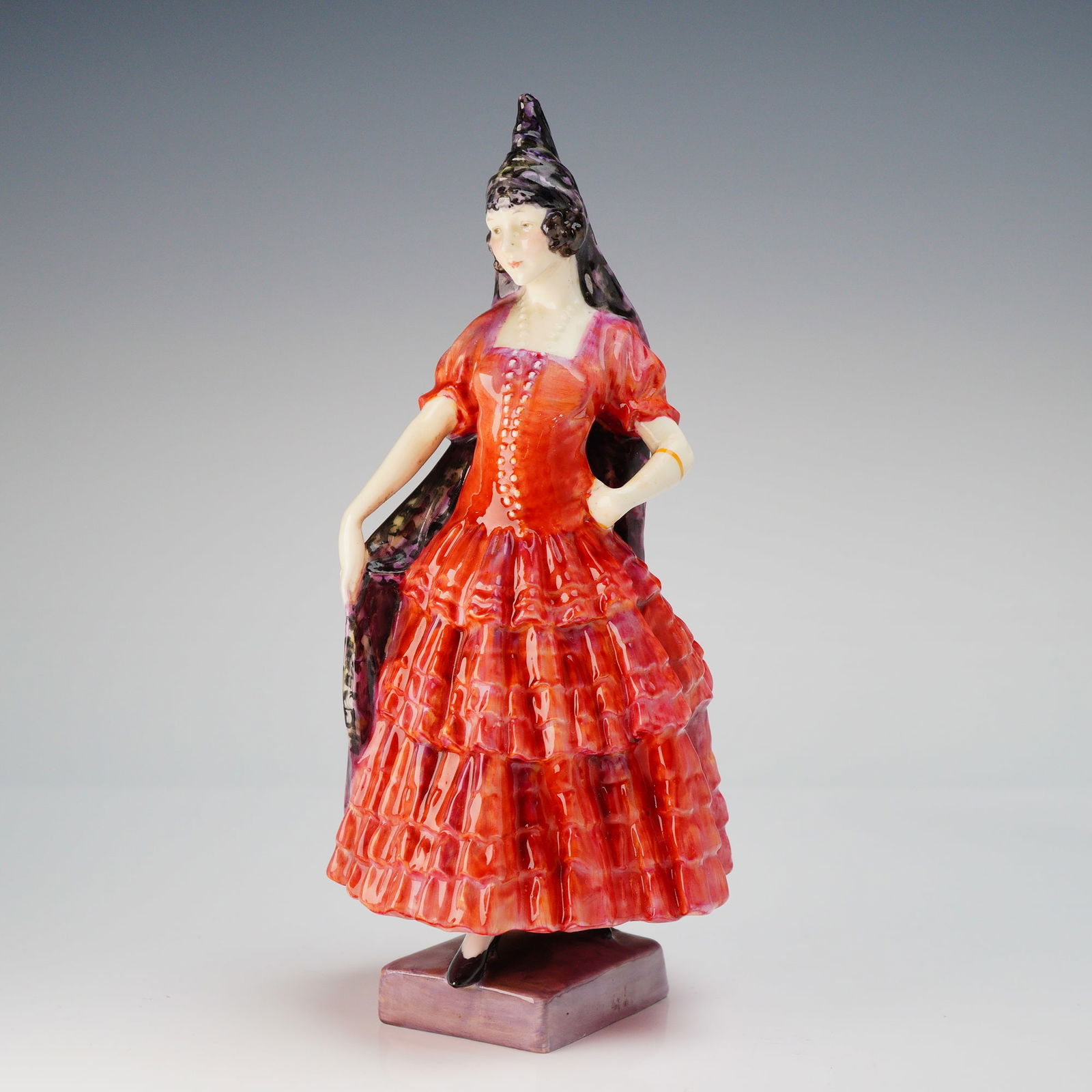 Royal Doulton Spanish Lady HN 1294 Porcelain Figurine: A single glazed porcelain figurine by Royal Doulton, identified as the model "Spanish Lady," HN 1294. The figure depicts a standing female dressed in a high-gloss tiered gown primarily in shades of ve