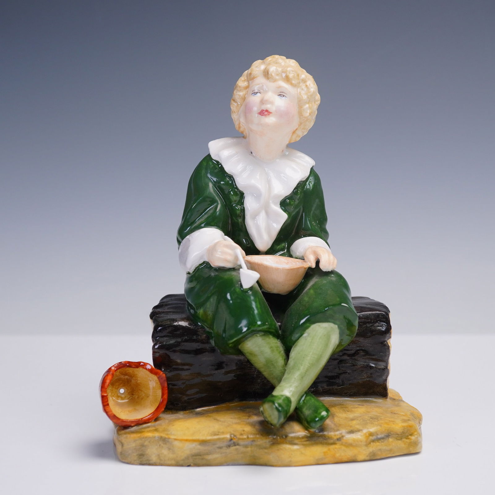 Reg Johnson and Sons Bone China Figurine, Bubbles: This hand painted bone china figurine titled Bubbles was produced by Reg Johnson and Sons in England. Depicting a curly-haired child in a green outfit with ruffled white collar, the figure is shown se