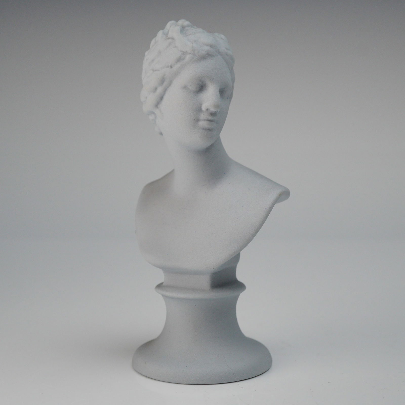 Wedgwood Pale Bisque Miniature Bust of Venus: A single miniature ceramic bust produced by Wedgwood, depicting a classical female figure. The sculpture is executed in a pale grey/blue matte stoneware, consistent with unglazed Jasperware or bisque