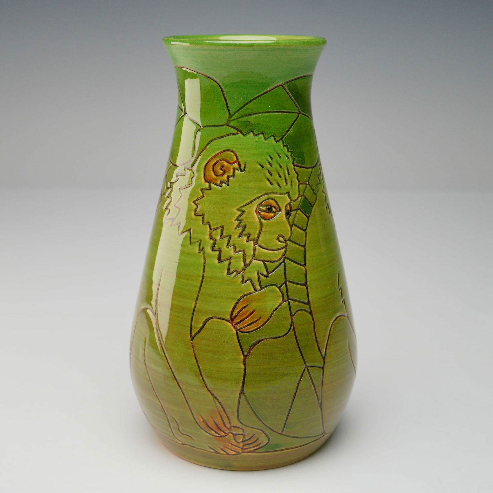 Dennis Chinaworks Bud Vase, Monkey Design: Dennis China Works studio art vase featuring an incised and hand-painted design of a monkey climbing among stylized foliage in green and earthy tones. The vase has a tapering cylindrical form with a f