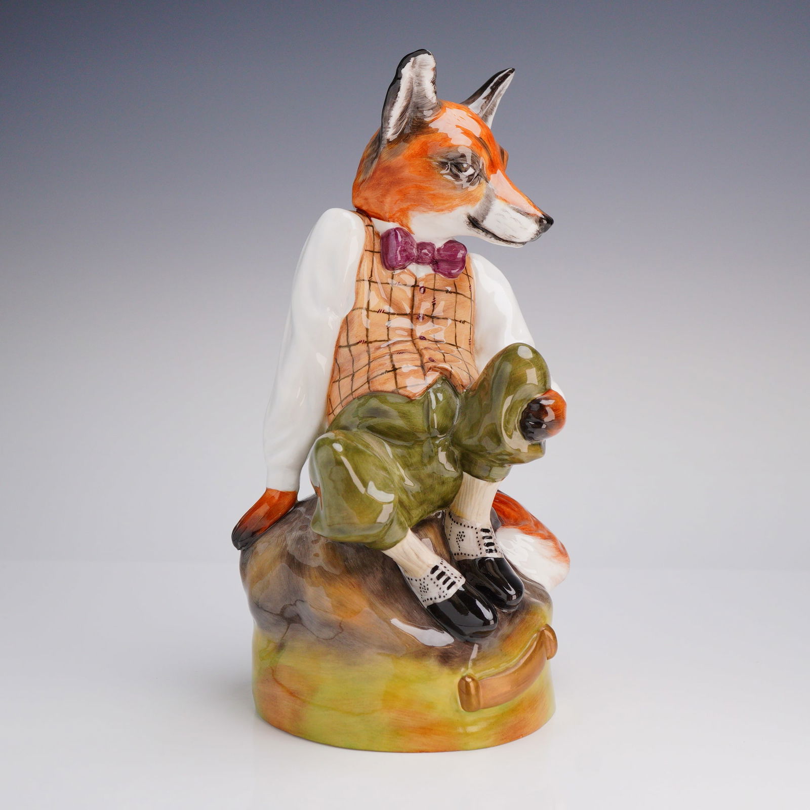 Royale Stratford Hand Painted Bone China Well-Dressed Fox Figurine: A hand-painted large figurine by Bloor China, Stoke-On-Trent, England, depicting an anthropomorphic red fox seated on a naturalistic base. The character figure is dressed in human attire, including a