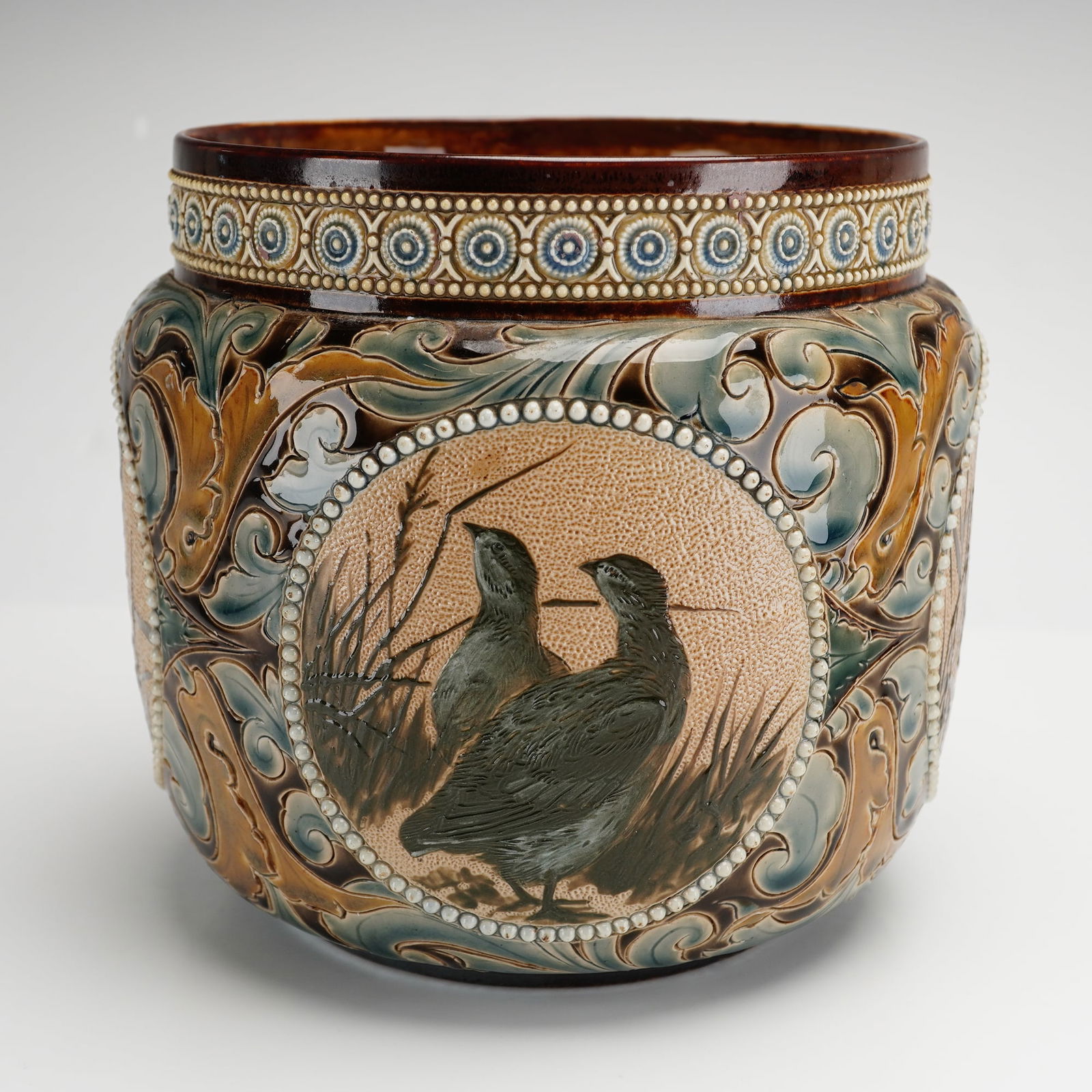 Doulton Lambeth Florence E. Barlow Stoneware Bird Vase: Designed by Florence E. Barlow (English, 1856-1909), Eliza Simmance (British, 1857-1935), and Emily E. Stomer (British, 19th century), is a short cylindrical English pottery vase. It features four cir