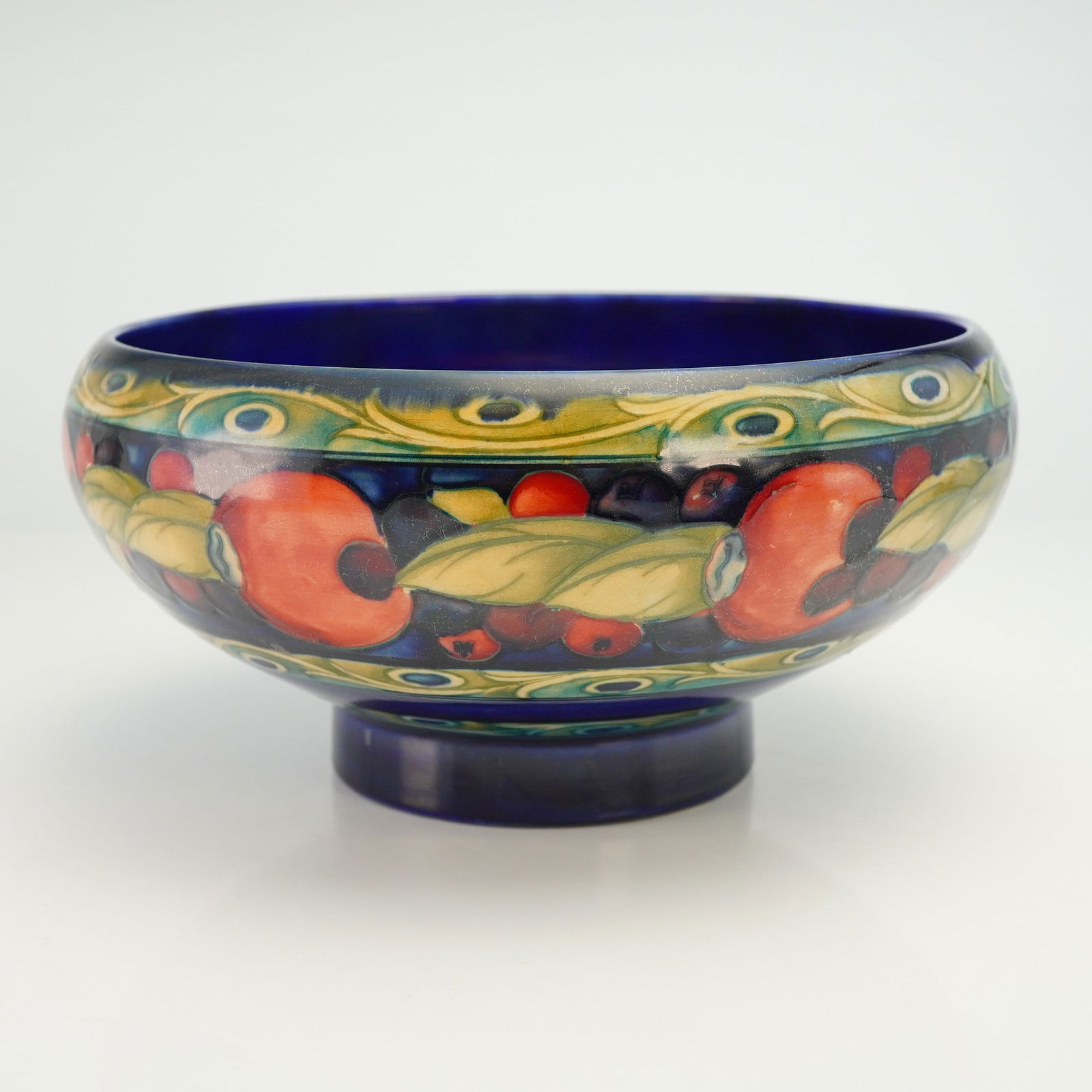 Moorcroft Pottery Banded Pomegranate Bowl: A richly decorated Moorcroft Pottery bowl featuring the classic Banded Pomegranate pattern. The shallow, gently rounded form is adorned with Moorcroft's signature tube-lined pomegranate motifs, framed