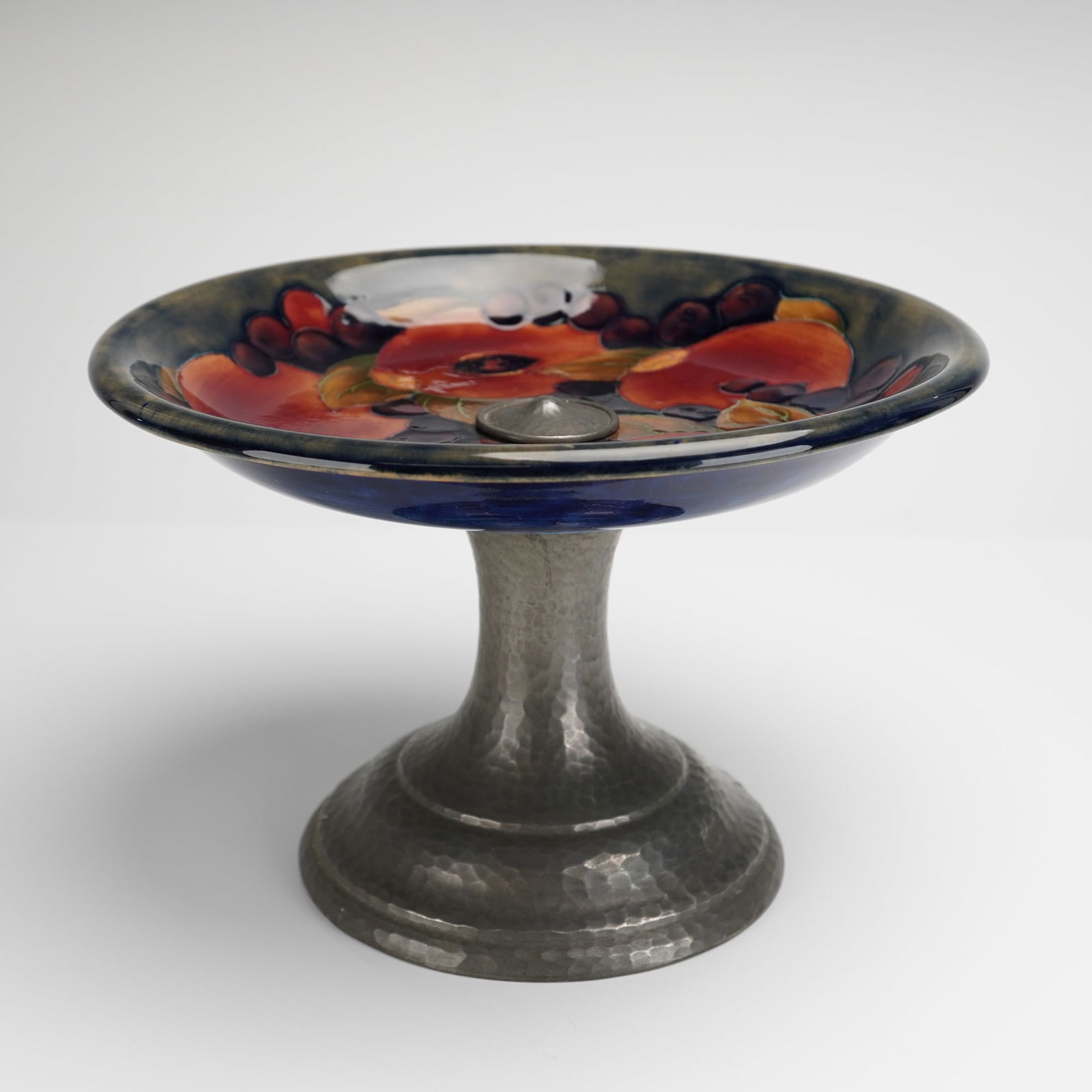 Moorcroft Pottery by William Moorcroft Pewter Mounted Tazza, Pomegranate: William Moorcroft tazza decorated in the Pomegranate pattern, with pewter mount, the base signed and with impressed marks. Dimensions: 8.50"W x 6.00"H