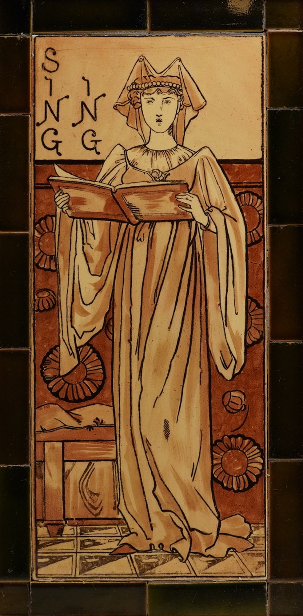 W.T. Copelands and Sons Framed Tile Panel, Singing: The central composition features a full-length female figure in long robes and a wimple, standing and reading from an open book or score. The design is executed in brown outline on a buff ground, high