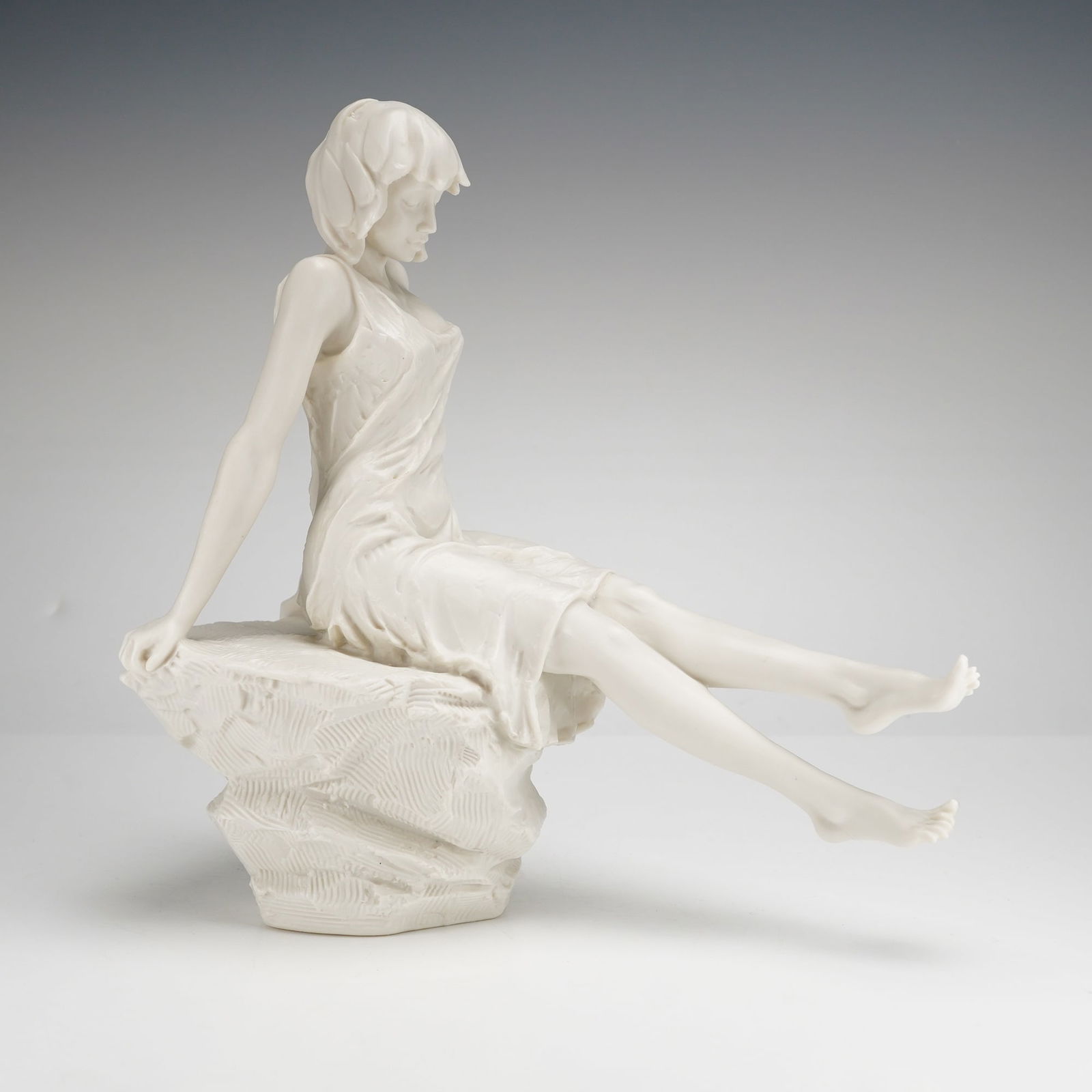 Royal Doulton Millennium Series Figurine, Girl on Rock: This Royal Doulton is a contemporary sculpture crafted from white bisque parian porcelain with a matte finish. The piece depicts a young woman in a simple sleeveless dress seated in a relaxed pose ato