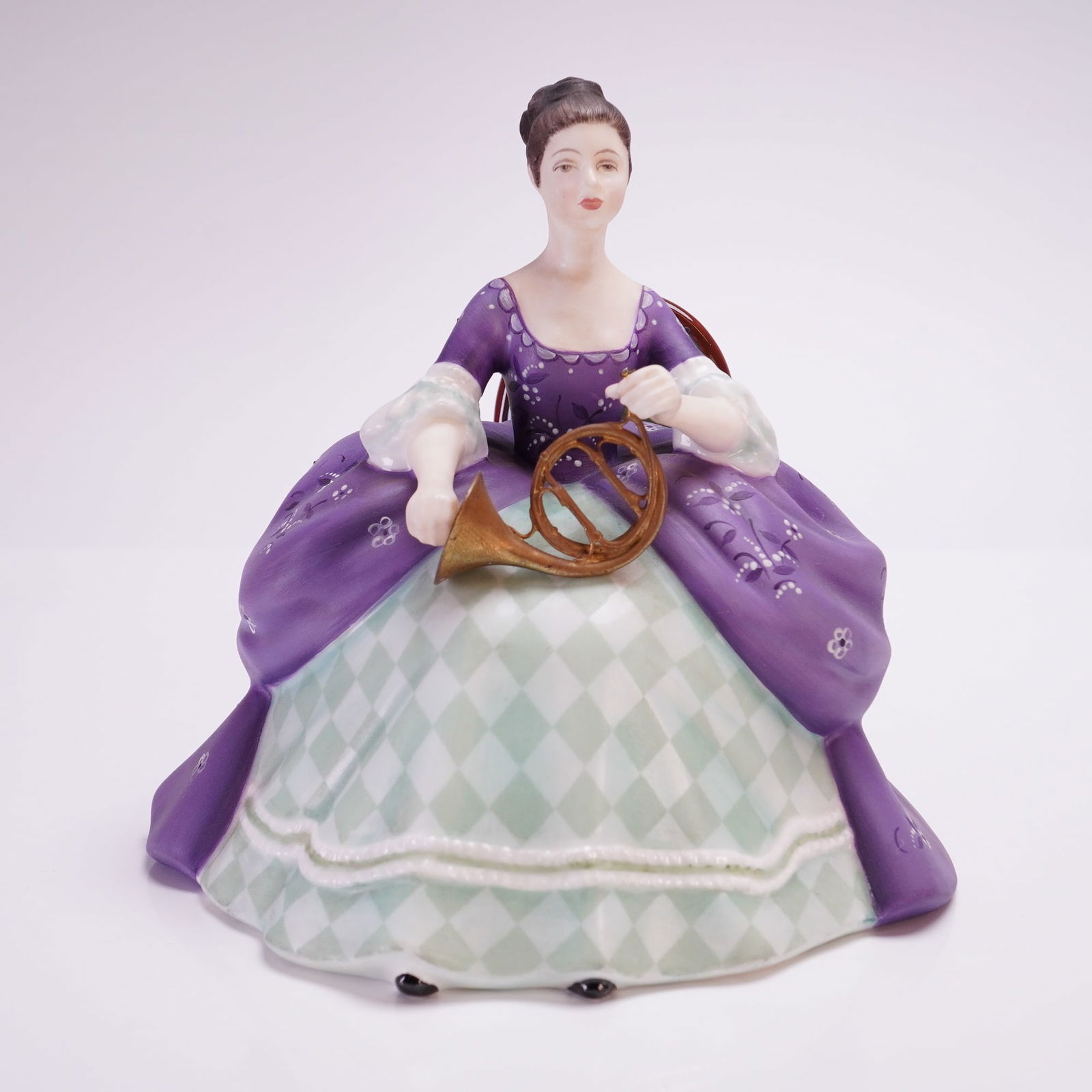 Royal Doulton Bone China Figurine, French Horn HN2795: This Royal Doulton was modeled by Peggy Davies and is dated 1975. The figure depicts a seated woman in 18th-century style attire holding a gold-toned musical instrument. The decoration consists of a p