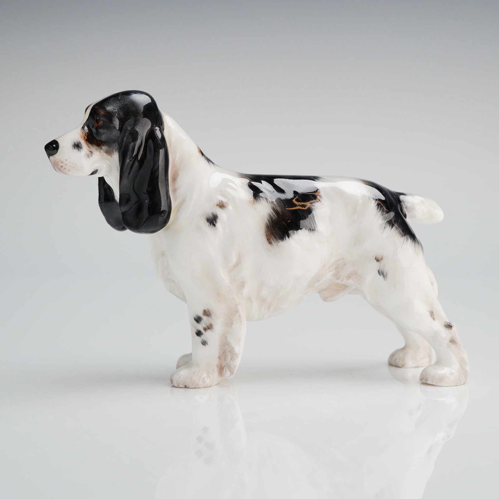 Royal Doulton Bone China Cocker Spaniel Figurine Model HN1078: A single glazed porcelain figurine depicting a standing Cocker Spaniel dog in a naturalistic style. The object is decorated in black and white with subtle brown speckling or roaning across the body, f